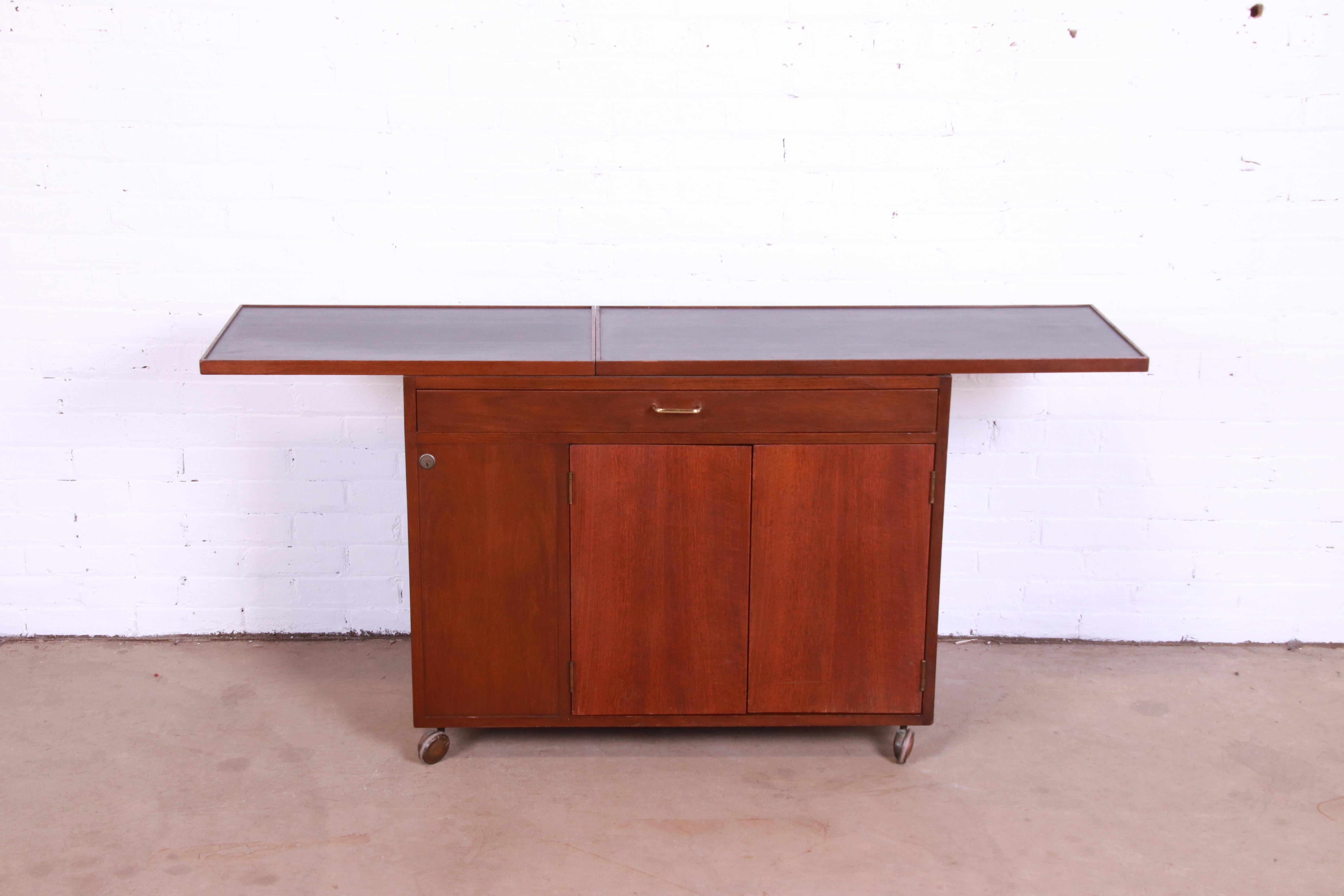 An exceptional Mid-Century Modern rolling bar cart

By Edward Wormley for Dunbar

USA, 1950s

Walnut, with extending faux slate top and original brass hardware.

Measures: 37.13