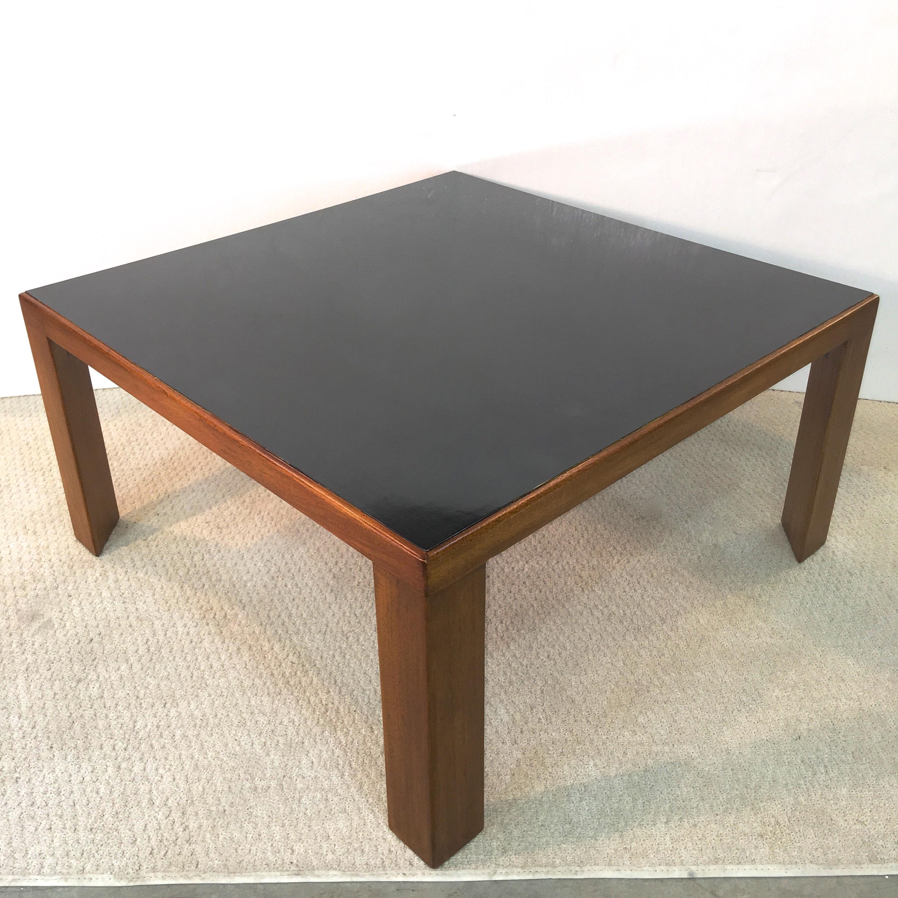 Late 1950s Edward Wormley for Dunbar model number 3374 square walnut cocktail table with distinctive three-sided legs and black micarta top. Understated elegance. Marked Dunbar on underside.