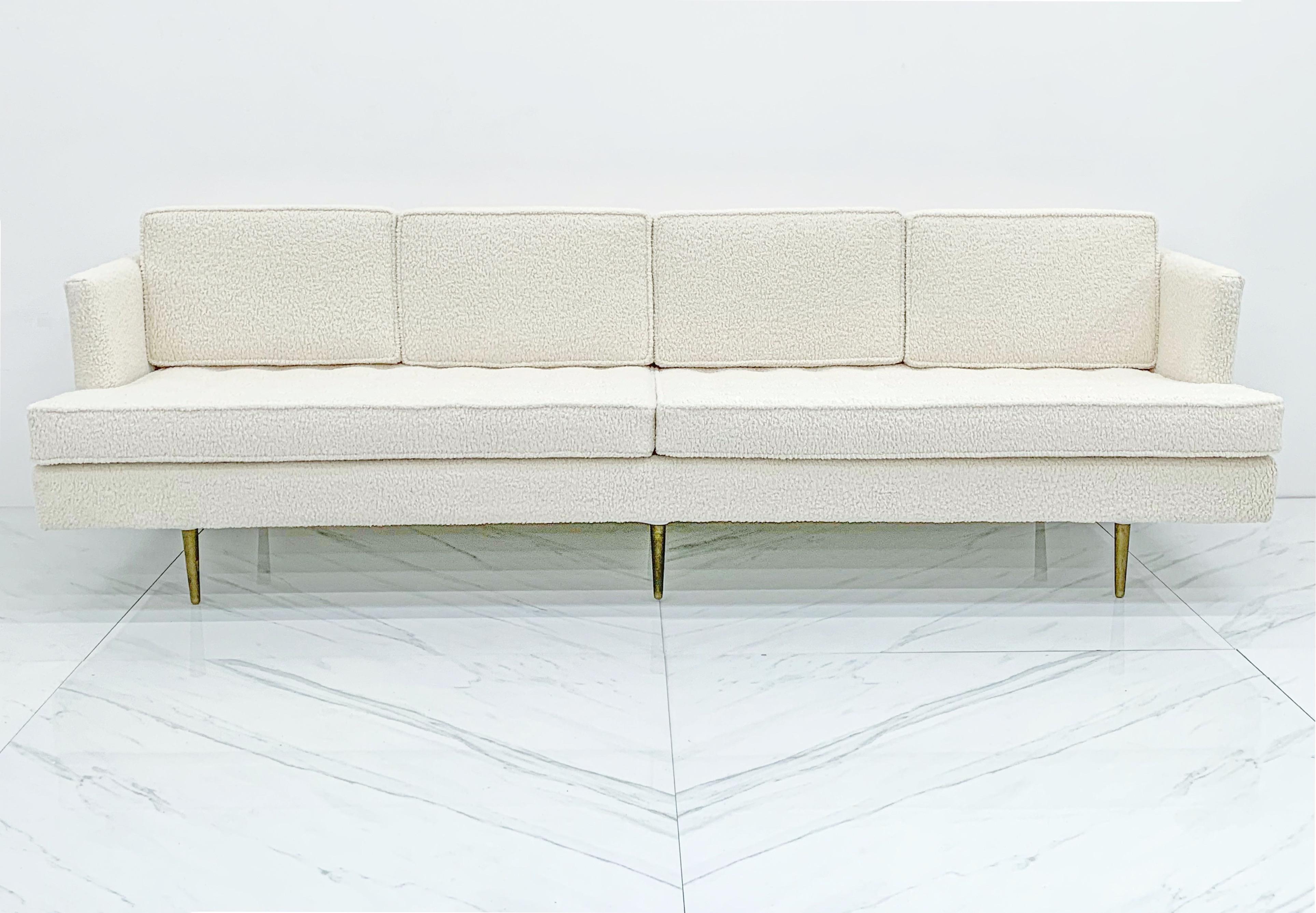 This incredible Model 4906-A four-seat sofa by Edward Wormley for Dunbar features gorgeous reupholstered white bouclé and six of Wormley's signature brass legs. Fine details such as the tufted seat cushions, conical brass legs and classic tuxedo