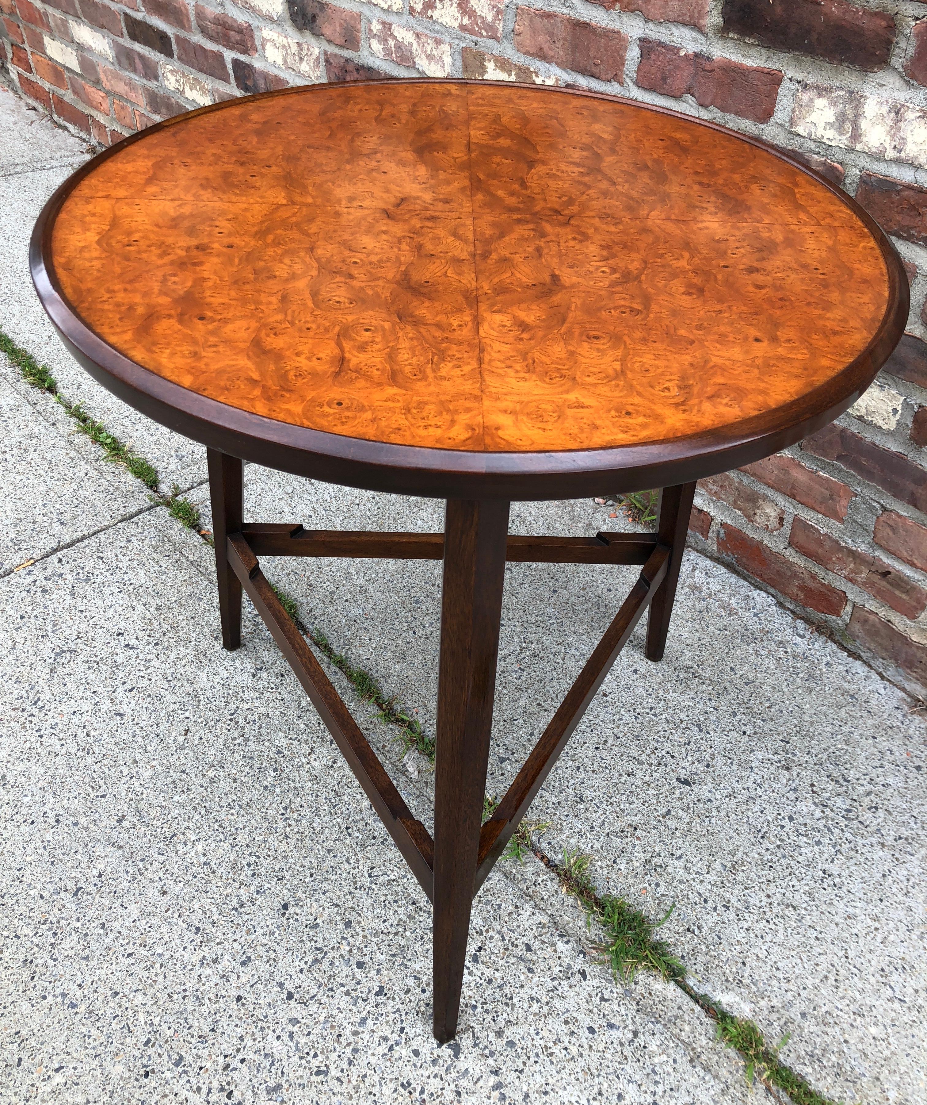 From the 1957 Janus line, this elegant side or snack table has a burl Carpathian Elm top on dark stained mahogany tripod base. Dunbar gold metal tag to the underside.
