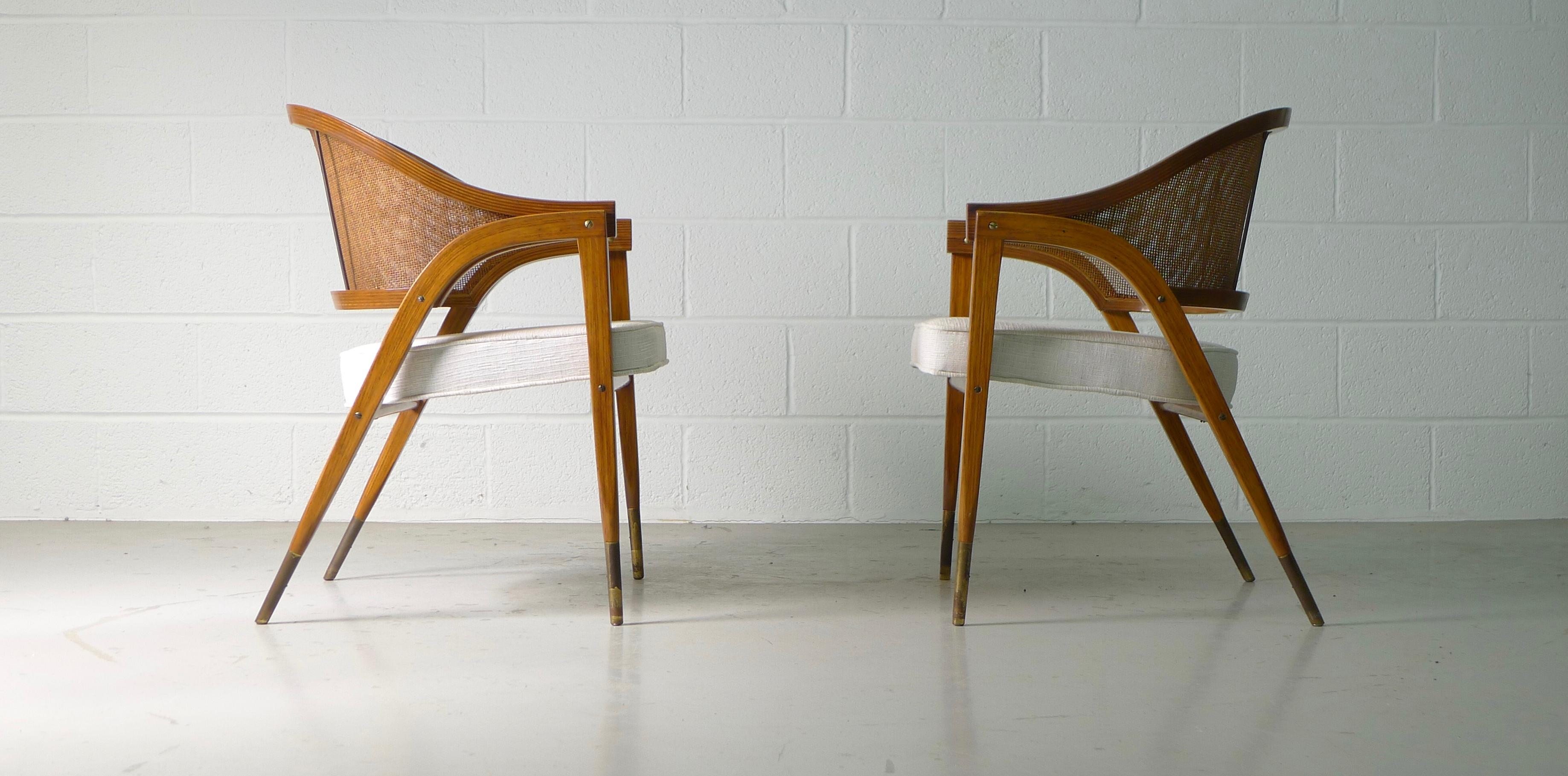 Edward Wormley for Dunbar, Berne, Indiana. Pair of armchairs model No. 5480 , designed mid-1950s and constructed of laminated ash, caned backrest, brass detailing and newly upholstered seat. Brass Sabots with nice original patina.