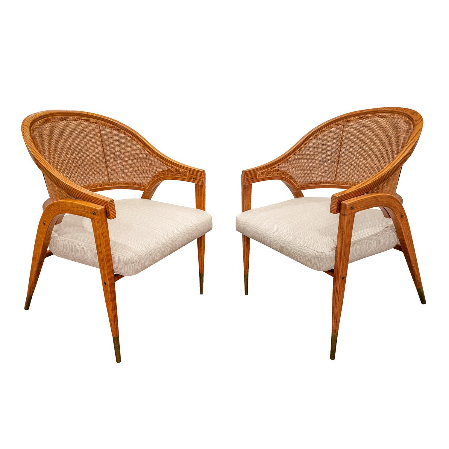 Pair of masterfully crafted lounge chairs model 5480 in laminated ash with caned back and brass sabots by Edward Wormley for Dunbar, American 1954.  These chairs are a tour de force of design.  One of the first pieces made of laminated wood, this