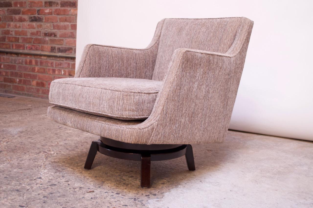 Swiveling lounge chair (model #5609) designed in 1956 by Edward Wormley for Dunbar. Swivel base is lacquered mahogany and retains its original stain. Base shows wear consistent with age and use, as shown. 
Frame has been reupholstered in a luxe
