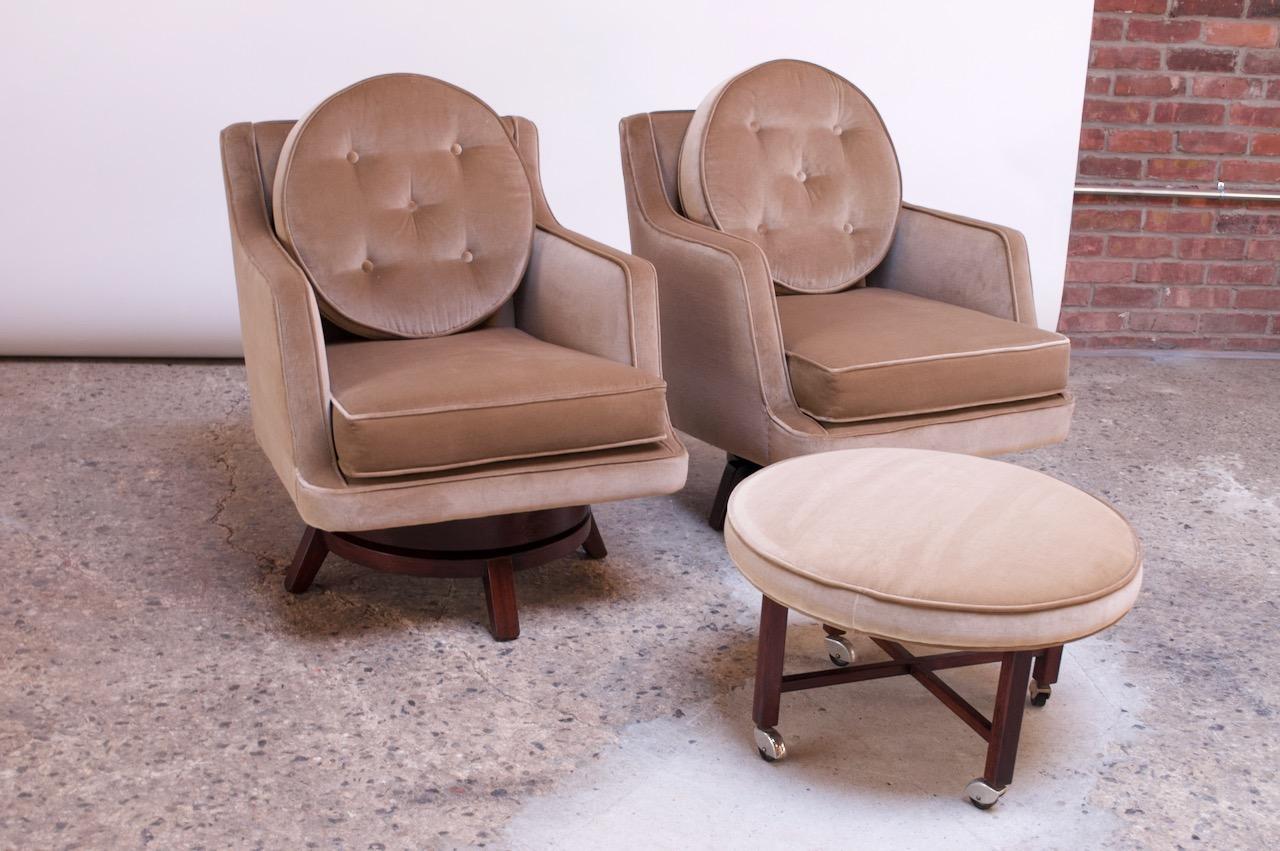 Pair of swiveling lounge chairs (model #5609) designed in 1956 by Edward Wormley for Dunbar. Swivel bases are stained mahogany and have been refinished (light wear remains). The bases differ slightly, as shown -- one is an early production (circa
