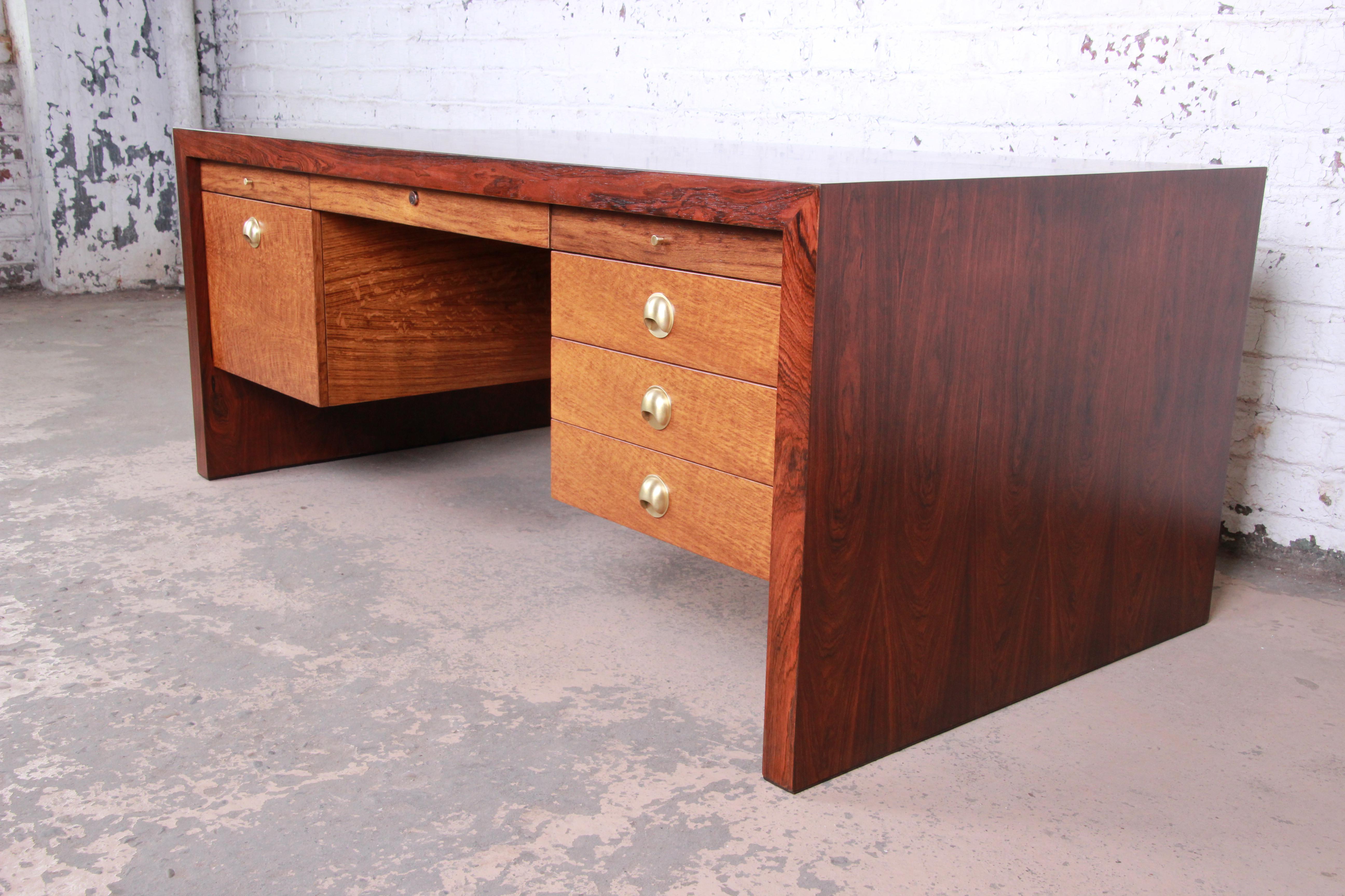 A rare and exceptional Mid-Century Modern executive desk by Edward Wormley for Dunbar Furniture. The desk features stunning rosewood grain and sleek mid-century design. It offers ample storage, with five drawers and two pull-out tablets in gorgeous
