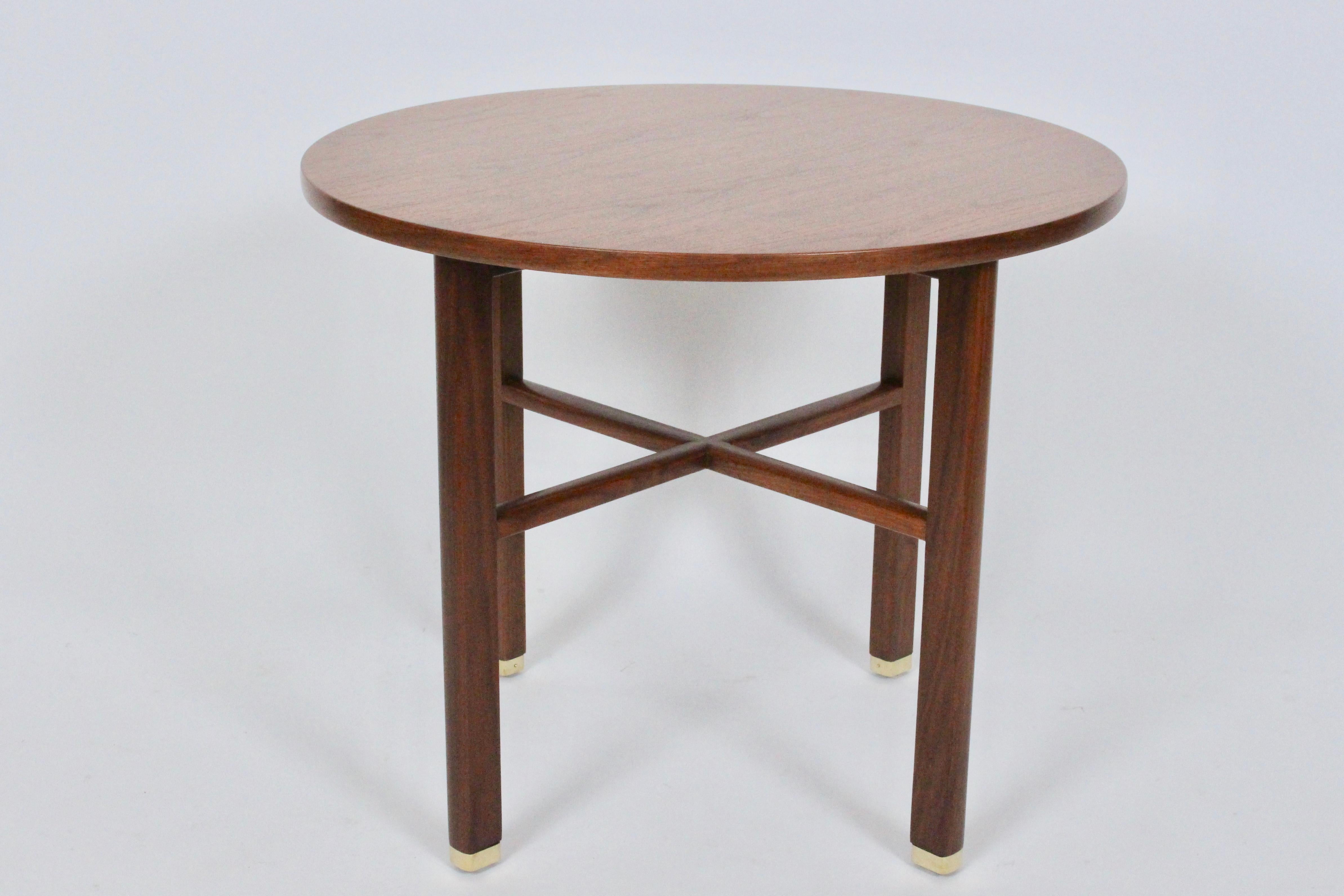 Classic Edward Wormley for Dunbar solid dark walnut round table. Nightstand. Featuring a round solid walnut surface, walnut stretchers, detailed with brass capped feet. Dunbar stamp to underside.  Kindly note that Professional Packaging costs will