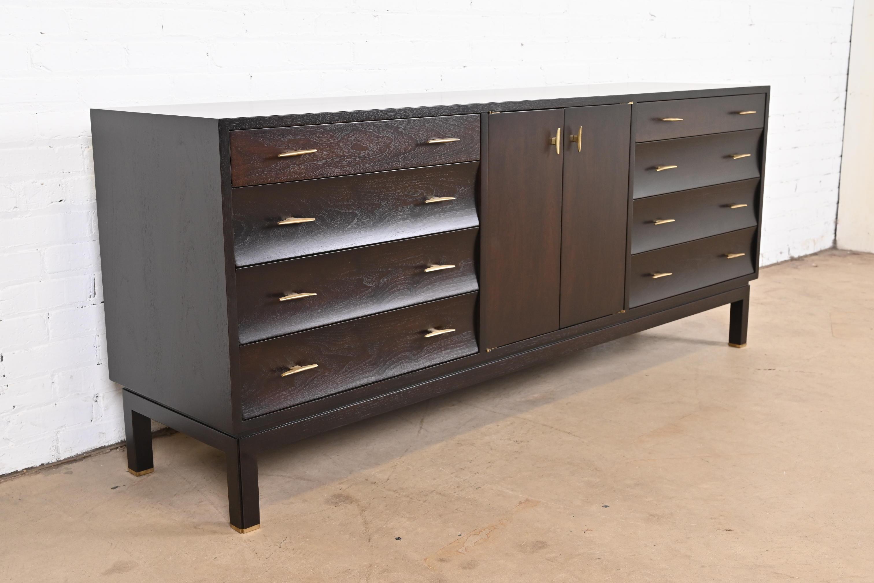 An exceptional Mid-Century Modern long dresser or credenza

By Edward Wormley for Dunbar Furniture

USA, 1960s

Sculpted dark mahogany, with unique concave drawer fronts, original brass hardware, and brass-capped feet.

Measures: 72