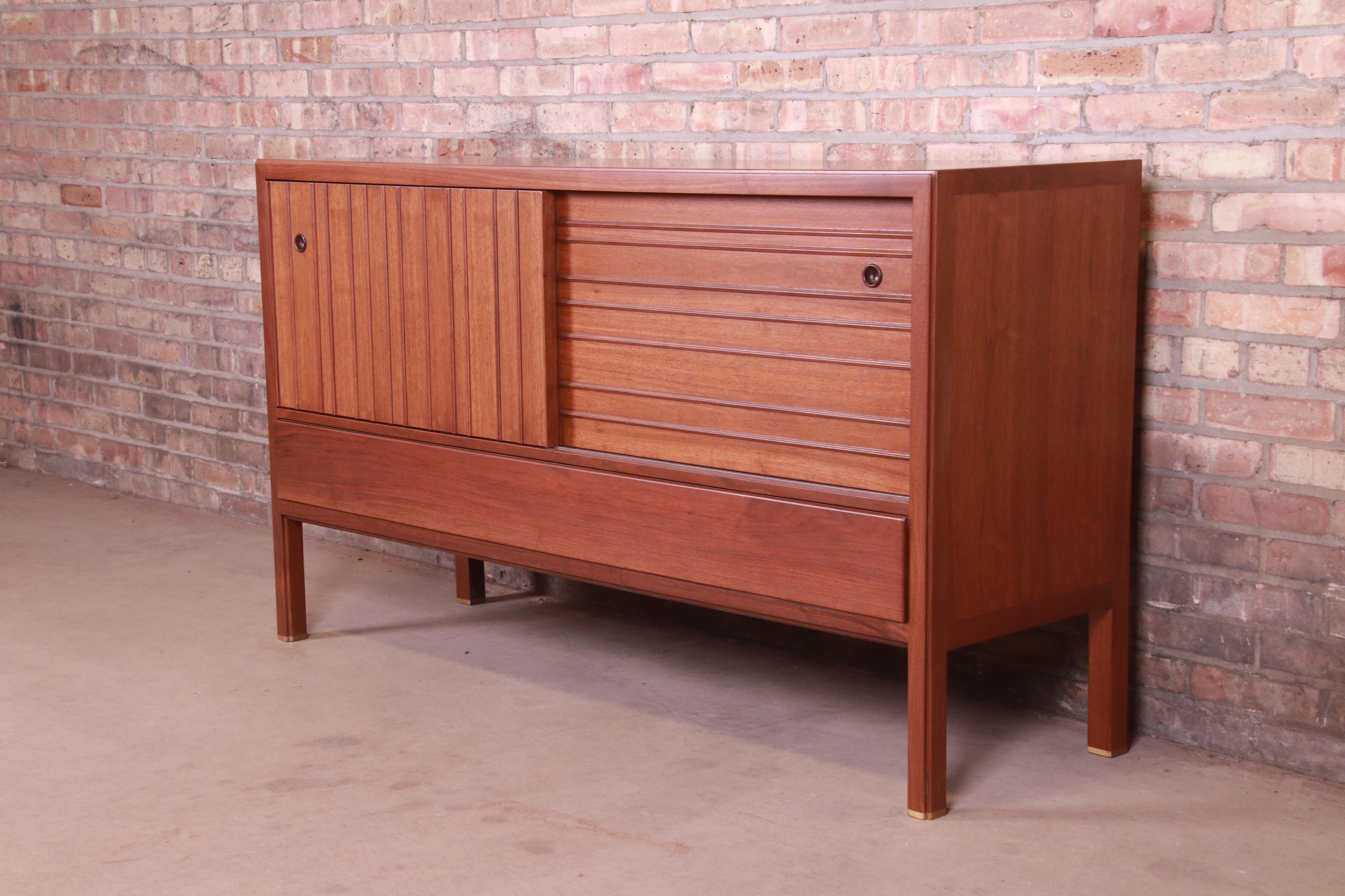 An exceptional Mid-Century Modern sideboard, credenza, or bar cabinet.

By Edward Wormley for Dunbar Furniture,

USA, 1950s

Sculpted walnut, with brass-capped feet.

Measures: 60