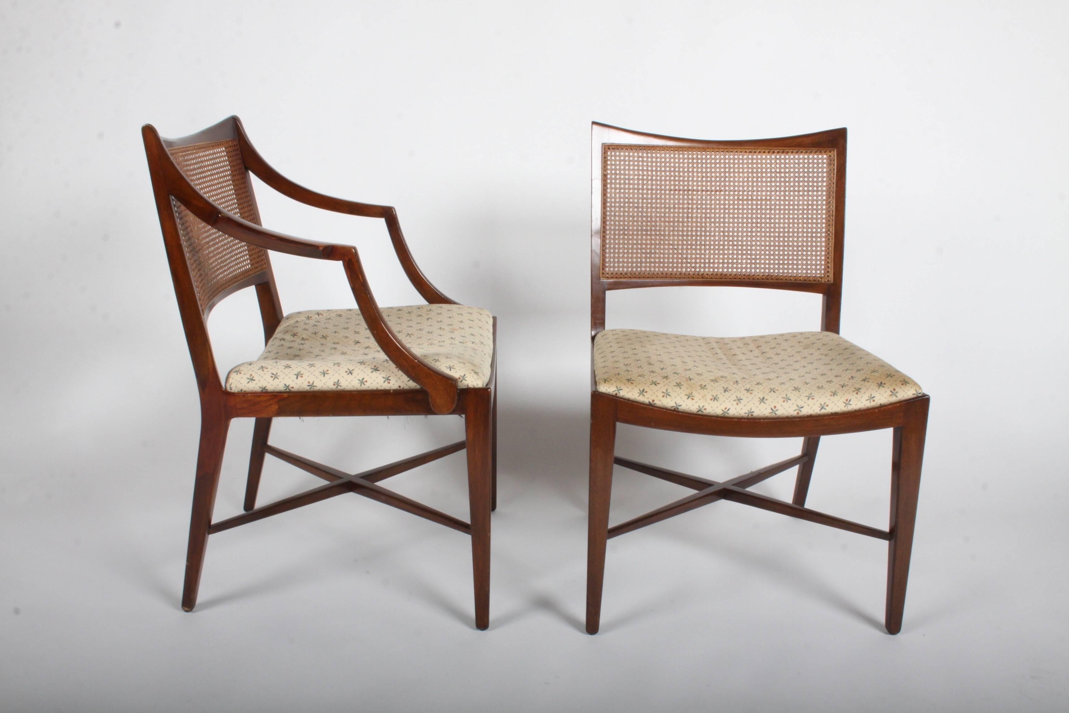 Elegant set of four Edward Wormley for Dunbar walnut frame and caned back dining chairs, two arms and two sides chairs. Curved back with caned panel and X-stretcher on legs. Includes frames to be refinished prior to shipping, seats are need of