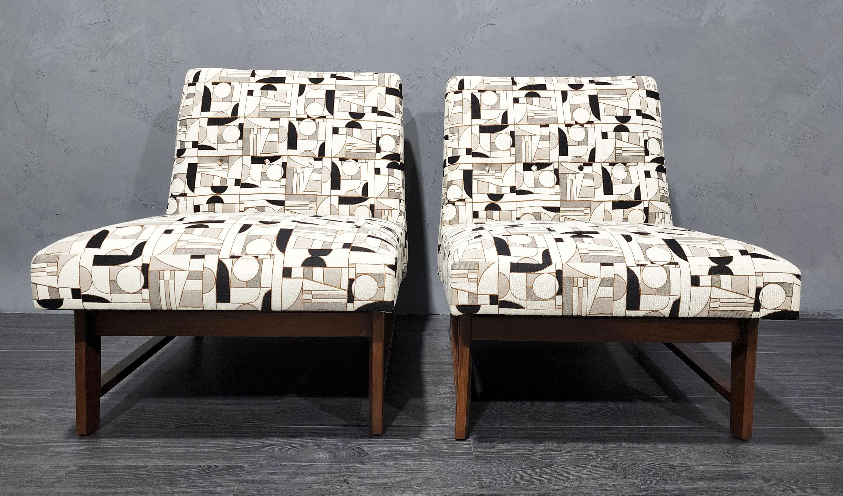 A pair of iconic slipper chairs by Edward Wormley for Dunbar. We have reupholstered these in a French woven fabric of very high quality. Colors include off-white, black , taupe and a coppery metallic.
