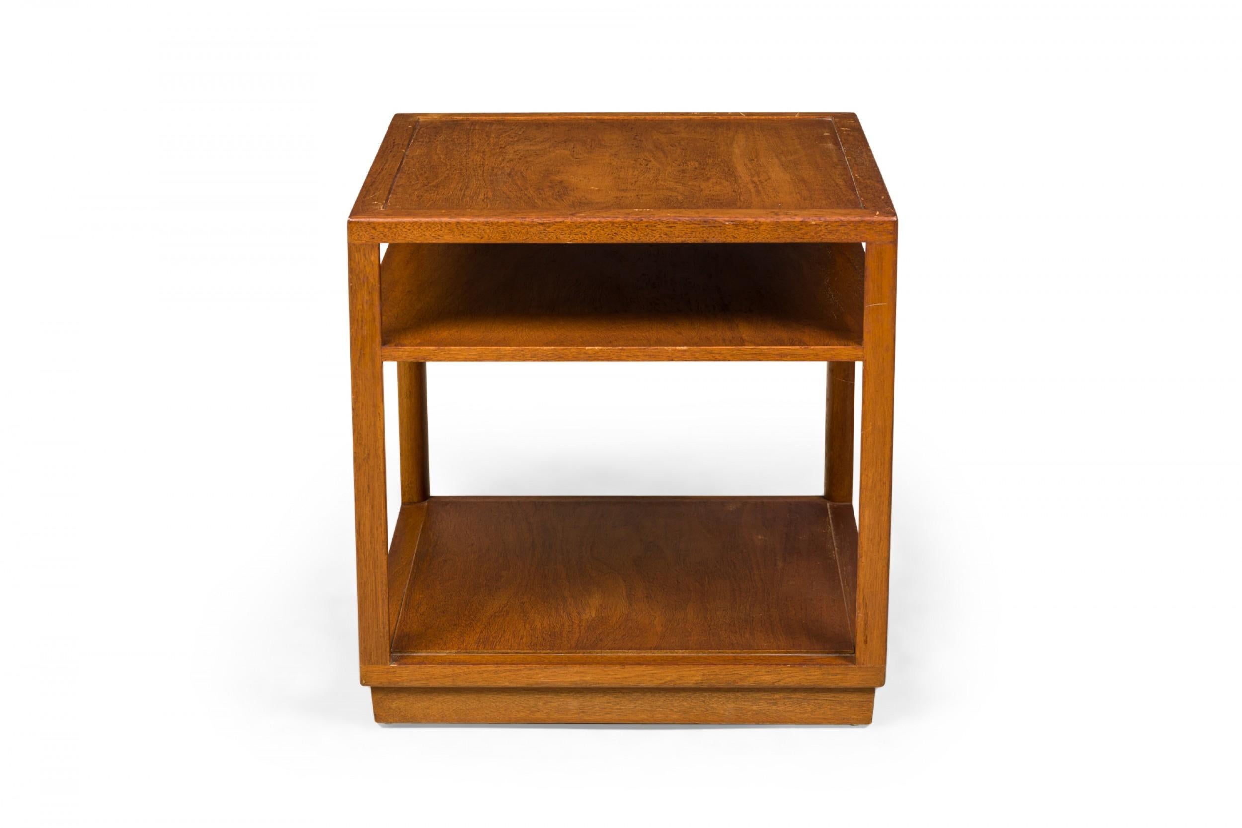 American Mid-Century square wooden end / side table with an open shelf below the square top, resting on a solid stepped base that creates as a taller lower shelf. (EDWARD WORMLEY FOR DUNBAR FURNITURE COMPANY)(Similar tables: DUF0649, DUF0650)
