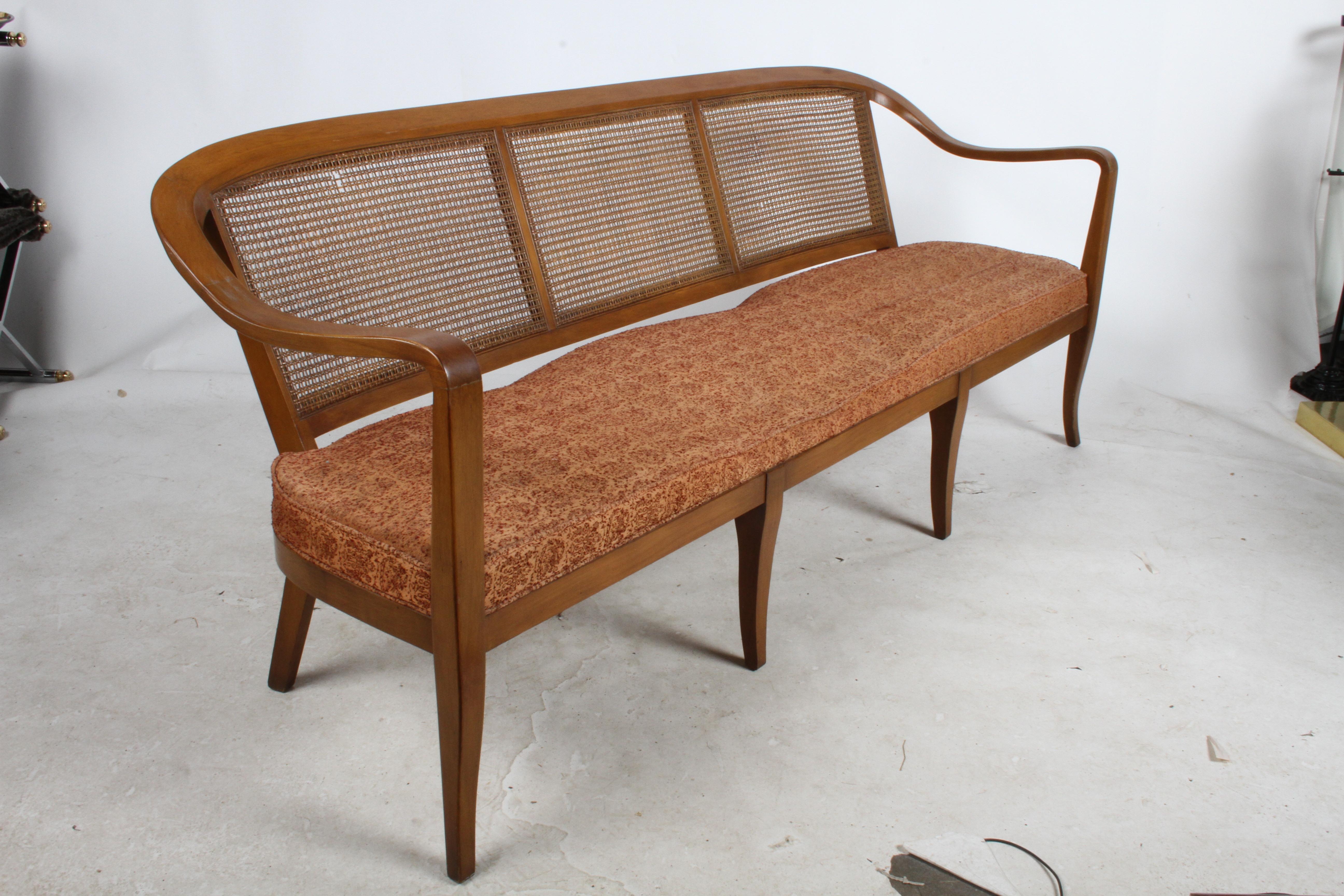 Rare midcentury sofa, settee or bench in the style of Edward Wormley for Dunbar with cane back and upholstered fixed seat. Chairs were featured in Architectural Digest in the mid-1950s. Shown in original condition, please note price includes