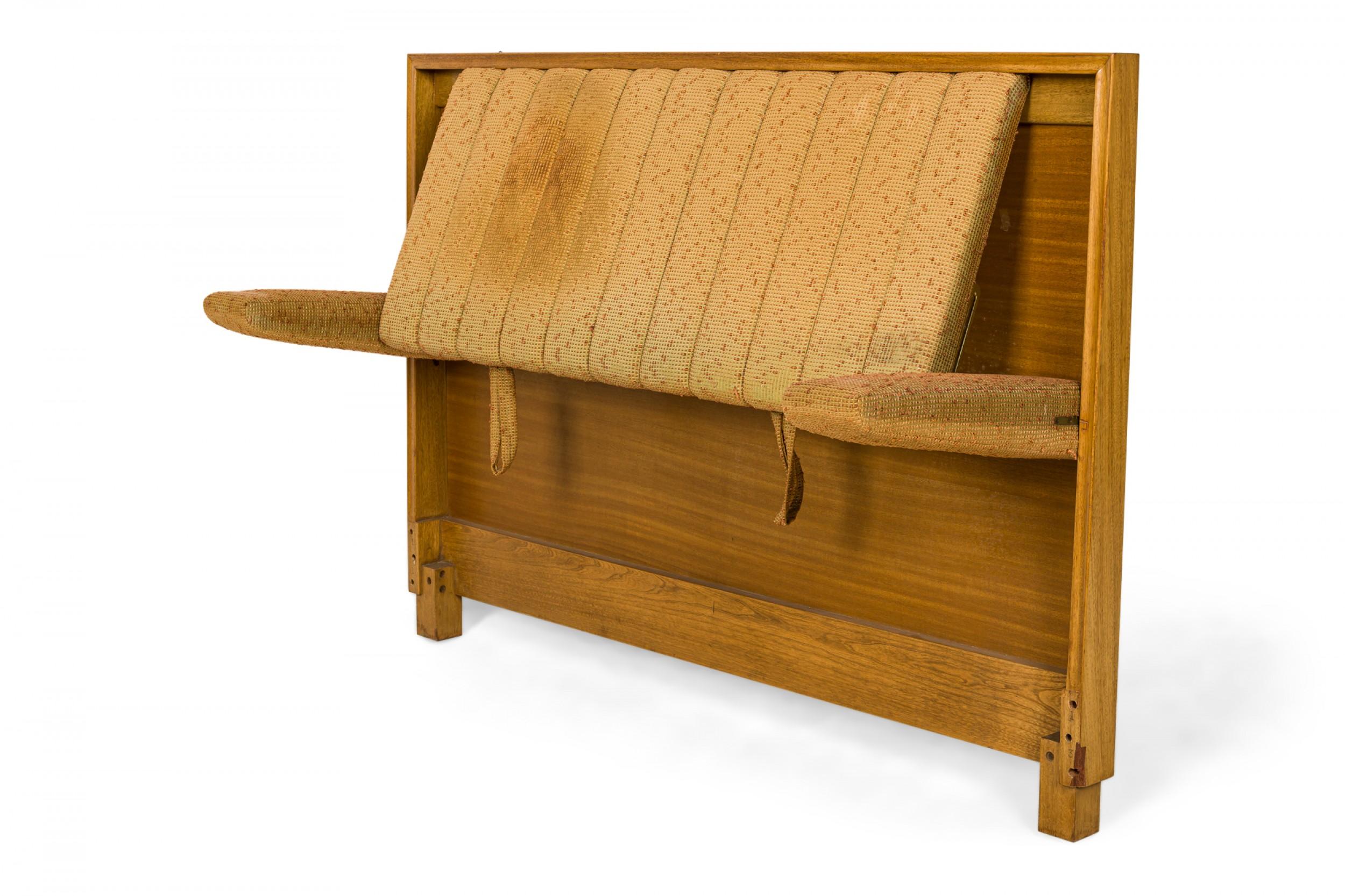 American Mid-Century single bed headboard with a walnut frame and beige and red textured fabric channeled upholstered center panel, which pivots outward as a backrest, flanked on either side by two fold down arms. (EDWARD WORMLEY FOR DUNBAR).
 