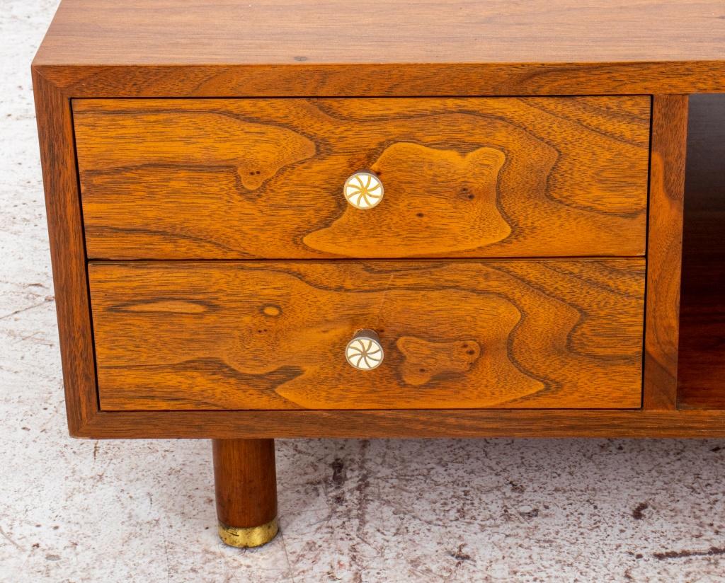 Edward J. Wormley (American, 1907-1995) for Dunbar walnut wood low table raised on tapered legs ending with gilt metal caps, having one open shelf and two drawers to side with metal handles, gilt metal maker plate to inside. In good vintage