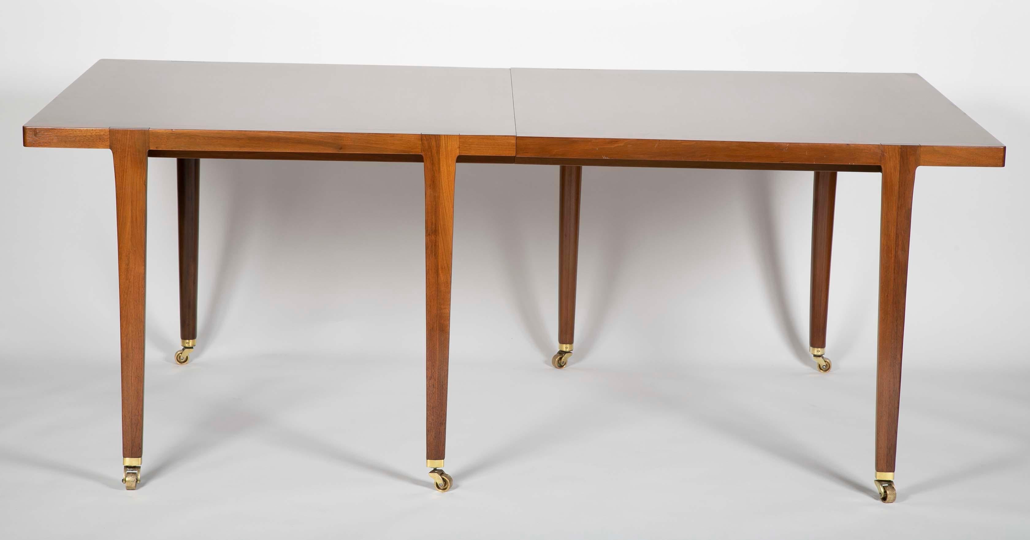 A Modern dining table designed by Edward Wormley for Dunbar. Walnut with brass casters. The table comes with two 18