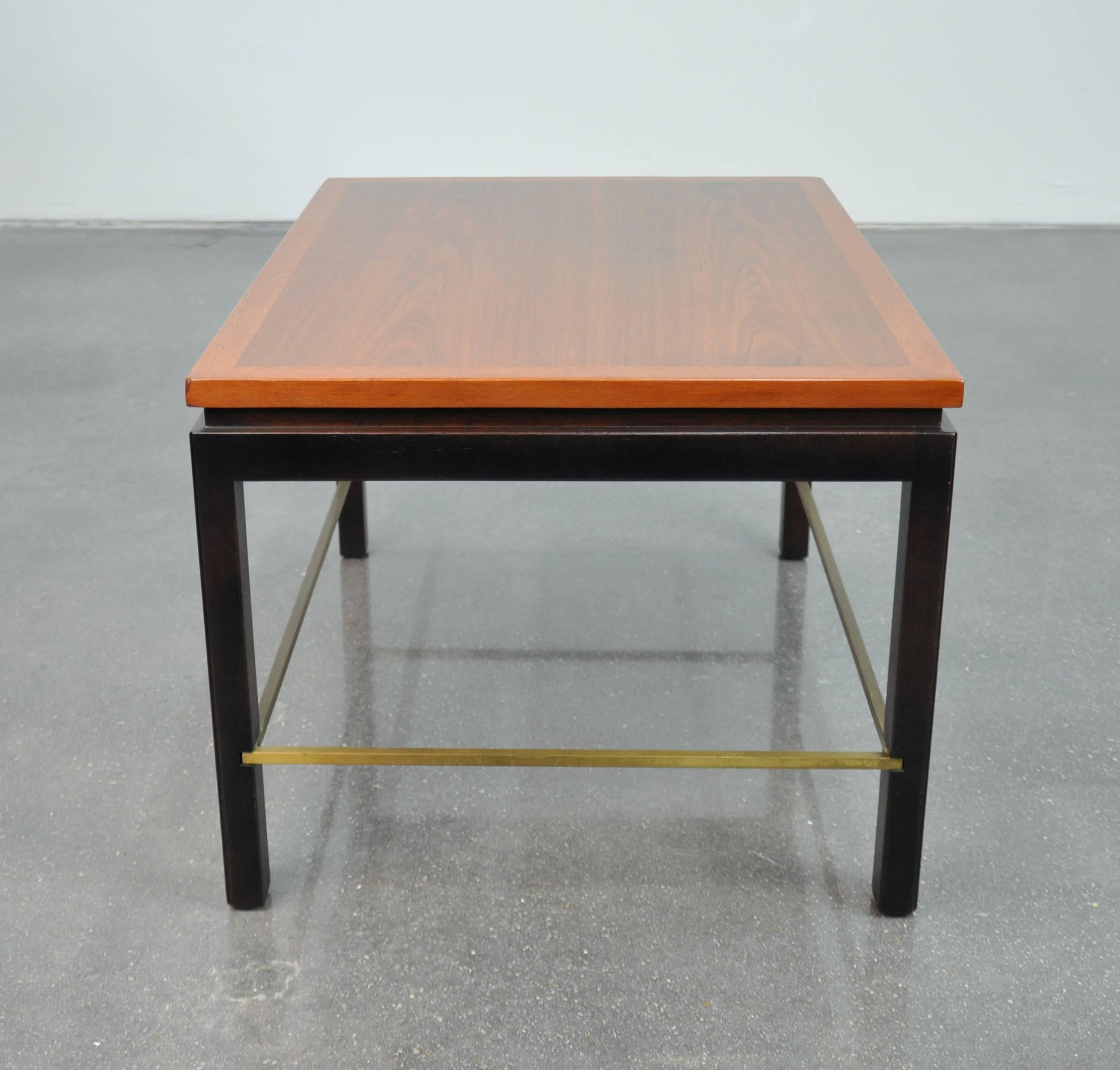 A vintage Mid-Century Modern model 310 end or occasional table designed by Edward Wormley for Dunbar and dating from the 1950s. The rectangular top appears to float over a recessed Parsons style ebonized mahogany base connected with inset brass