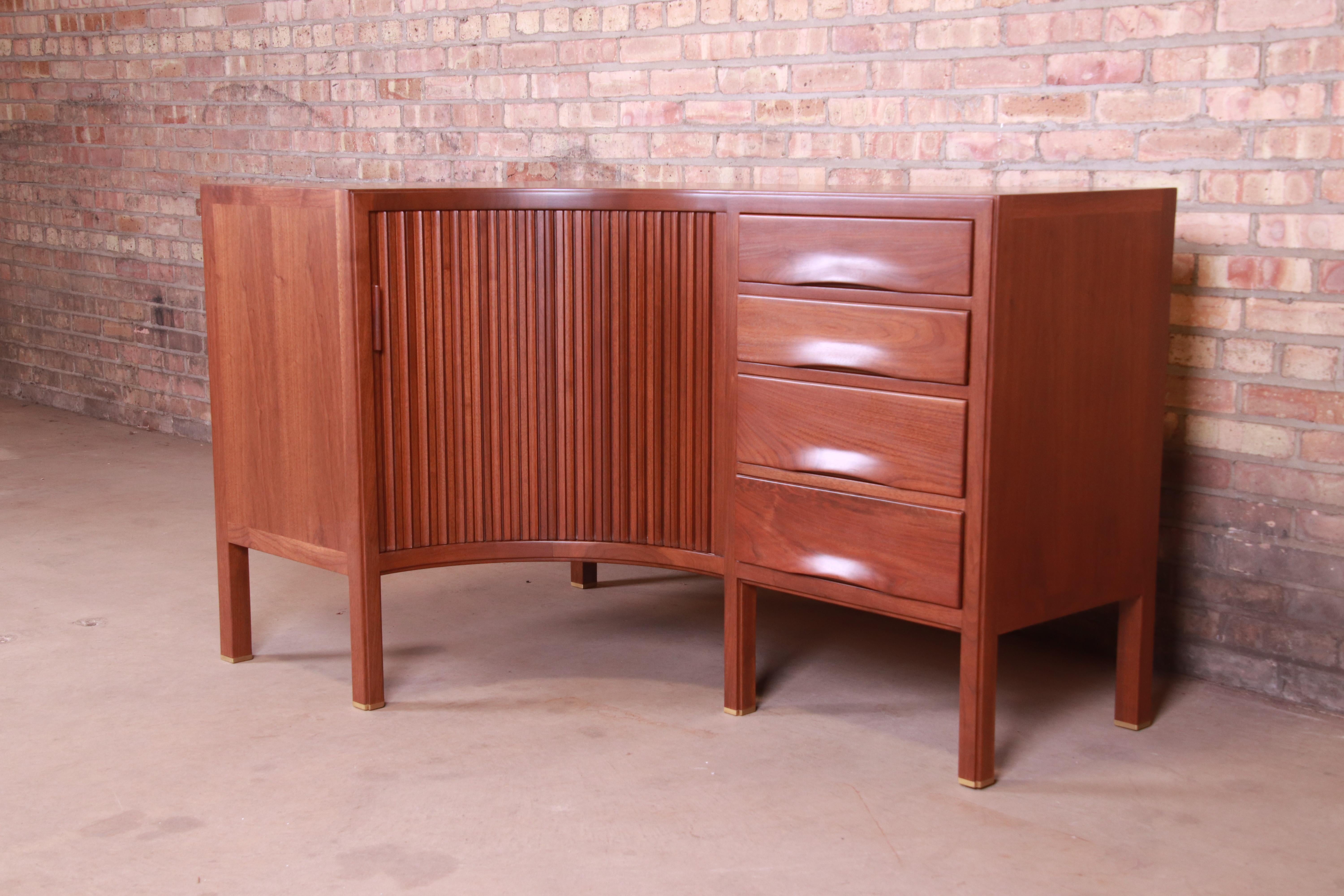 A rare and exceptional Mid-Century Modern corner credenza

By Edward Wormley for Dunbar Furniture

USA, 1950s

Sculpted walnut, with curved tambour door and brass-capped feet.

Measures: 35