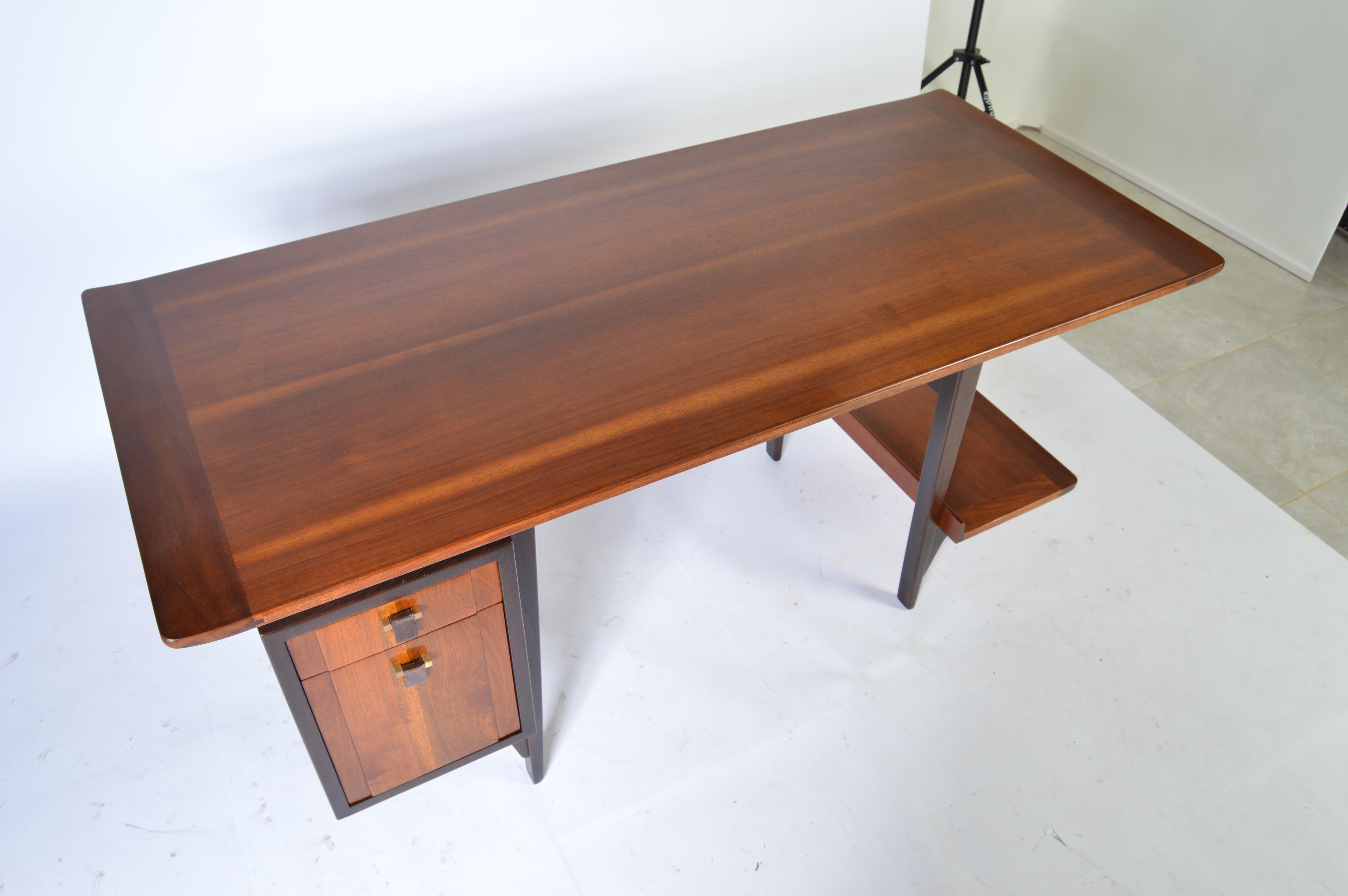 A rare masterfully designed writing desk designed by Edward Wormley having a single bank of drawers, lap pencil drawer and display shelf.
A combined construction of walnut, rosewood and brass hinged rosewood pull tabs make this desk stand out above