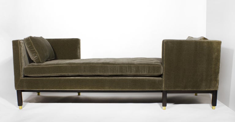Dunbar tête-à-tête sofa designed by Edward Wormley for Dunbar. Upholstered in a soft mossy olive green perennials velvet. The base has been professionally refinished and the brass sabots have been hand polished and relacquered. All new foam and