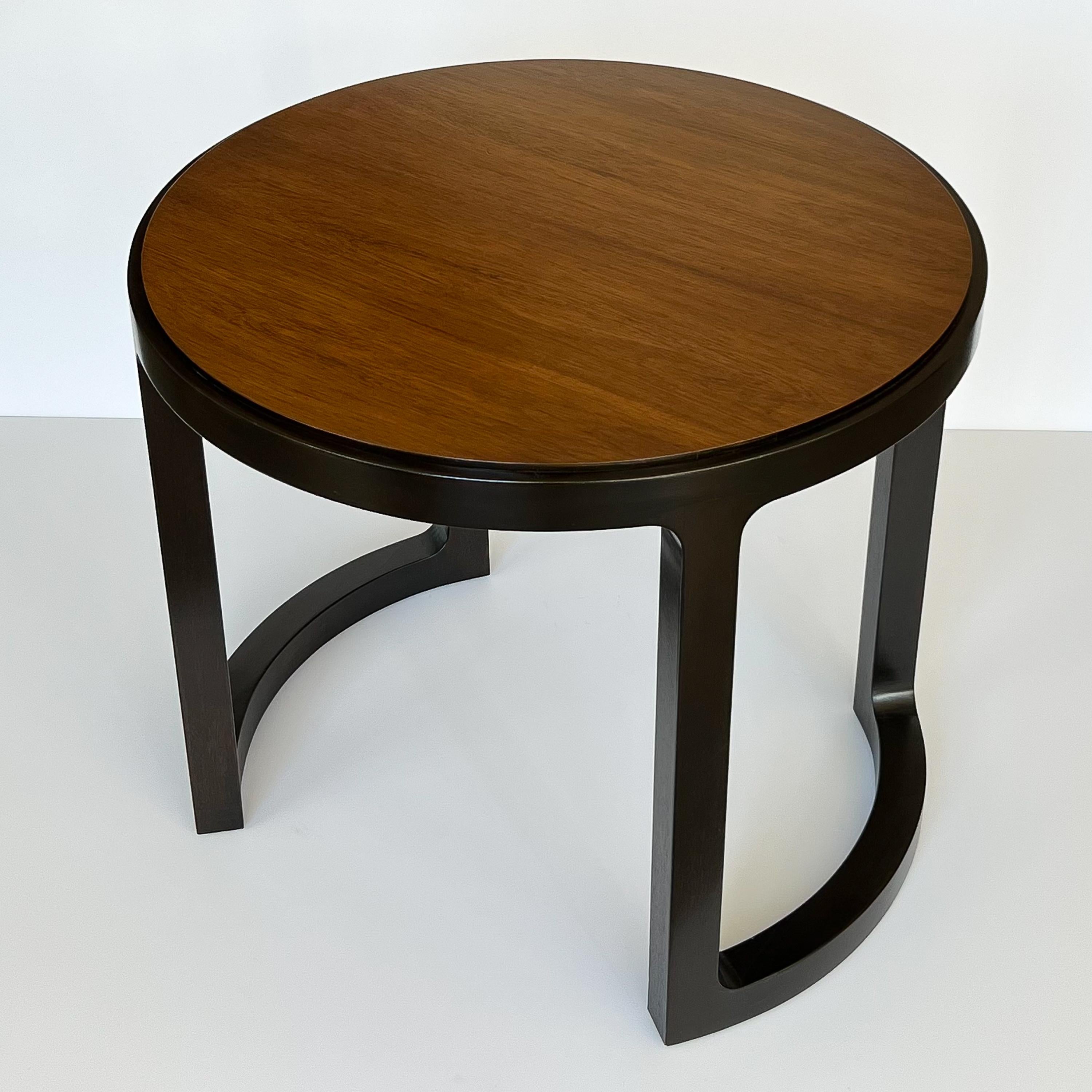 A stunning Mid-Century Modern walnut and mahogany round end table or side table by renowned designer Edward Wormley for Dunbar Furniture, circa 1960s. This exquisitely designed piece offers a perfect blend of form and function, making it an