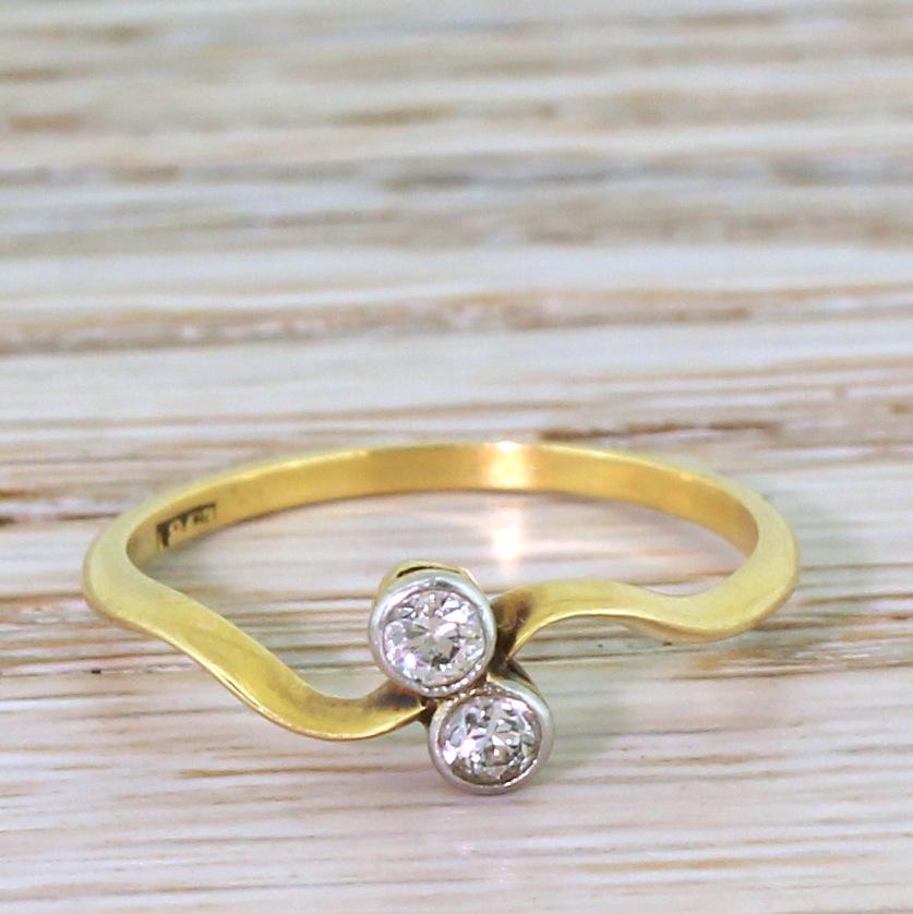 A very lovely diamond crossover ring. The bright and white European cut diamond are rubover set in platinum and set either side of a slim and sweeping 18k yellow gold shank. Wonderfully elegant.

Cut – Old European cuts.

Colour – H.

Clarity –