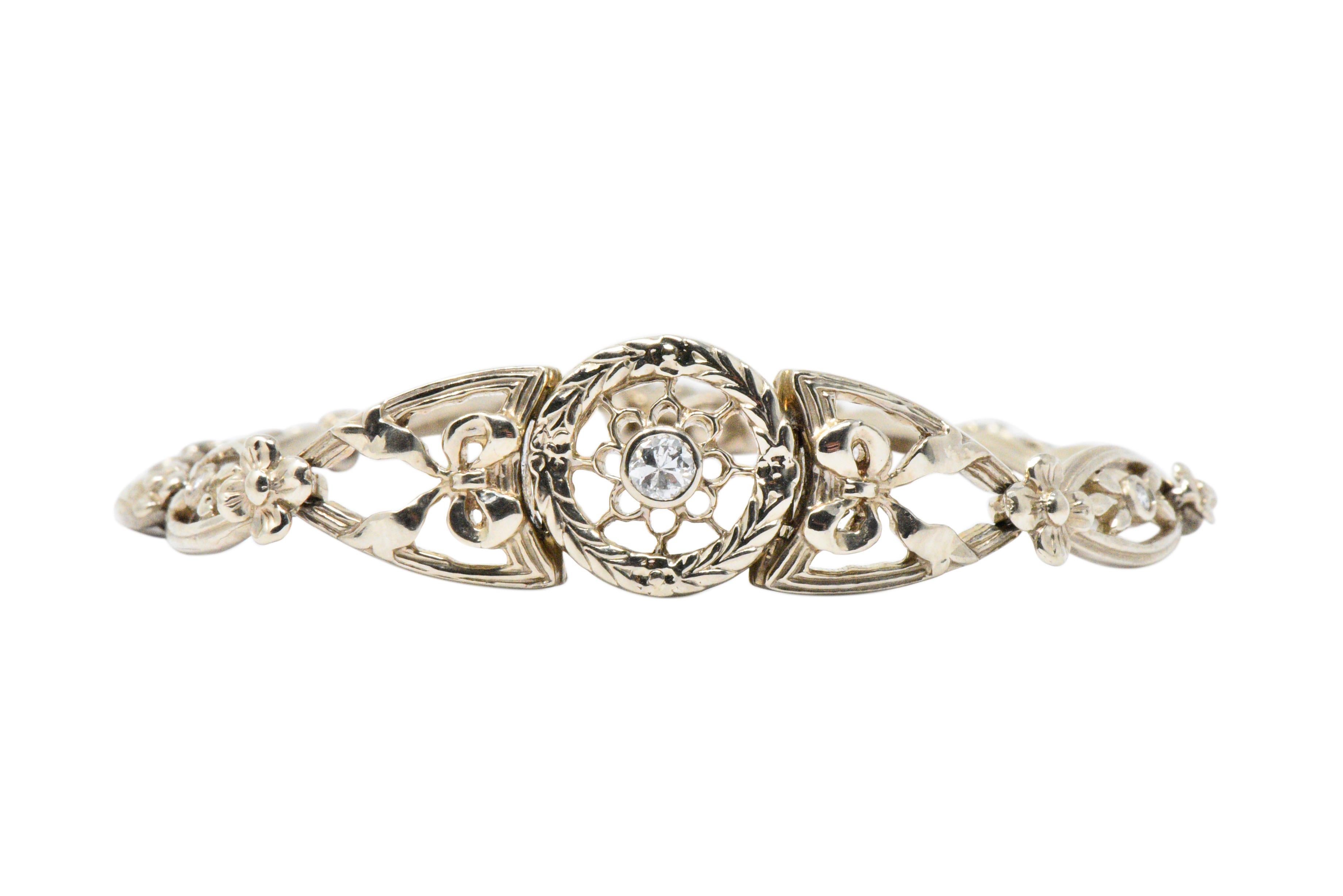 Link style bracelet centering a transitional cut diamond weighing approximately 0.10 carat, eye-clean and white

Bezel set within a circular central station featuring a pierced radiating design surrounded by deeply engraved foliate

Links are