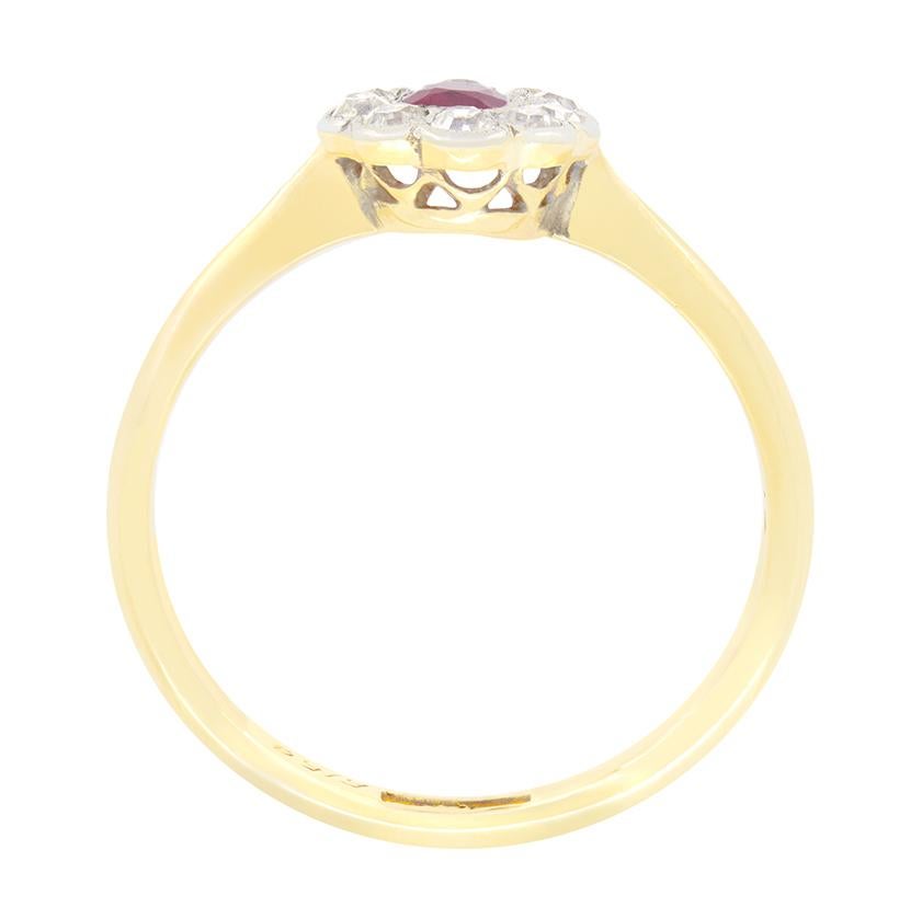 A red ruby is surrounded by sparkling old cut diamonds in this beautiful Edwardian cluster ring. The oval cut ruby is a 0.30 carat stone with the surrounded diamonds creating a vivid contrast. The old cut diamonds total of 0.50 carat with matching