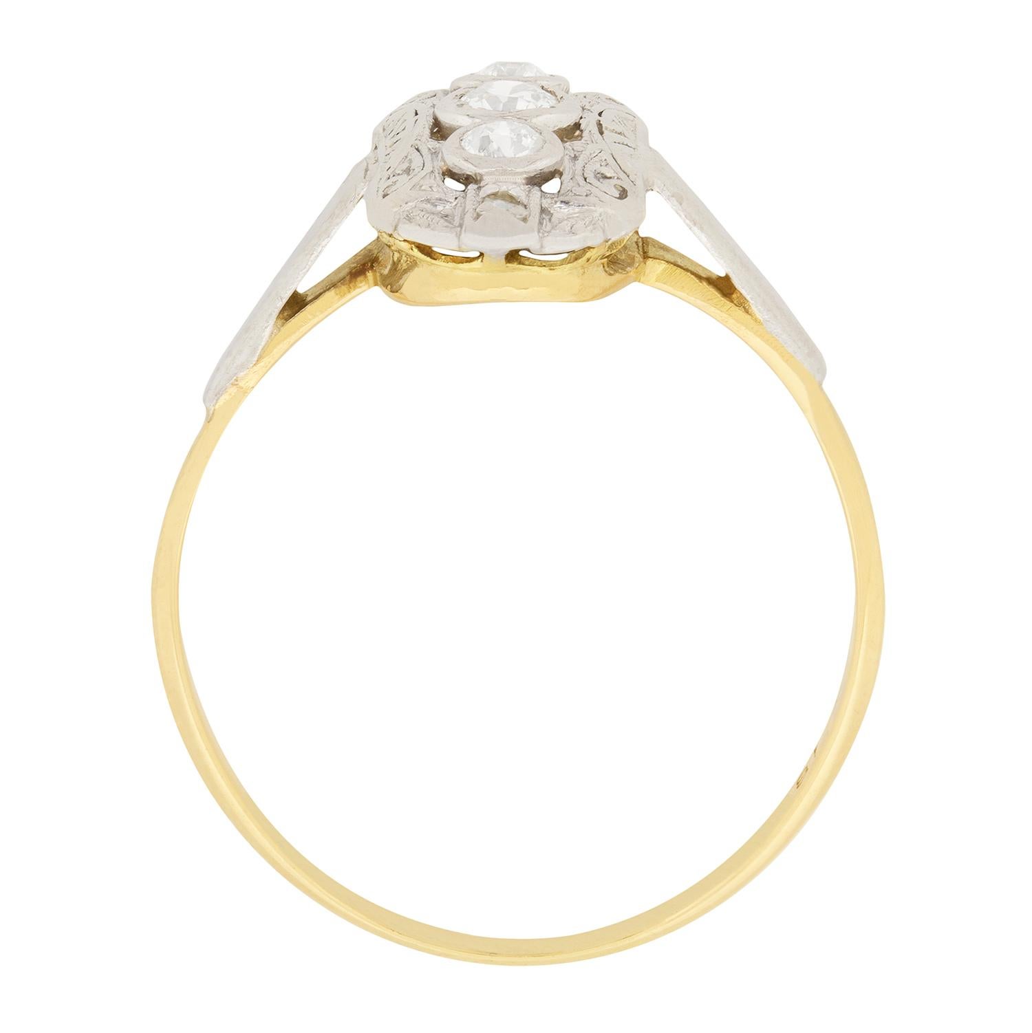 This diamond cluster ring is a lovely example of the style of the Edwardian period. A 0.15 carat old cut diamond sits in the centre, while there is a 0.10 carat rose cut diamond above and below. The diamonds are rub-over set in a finely engraved