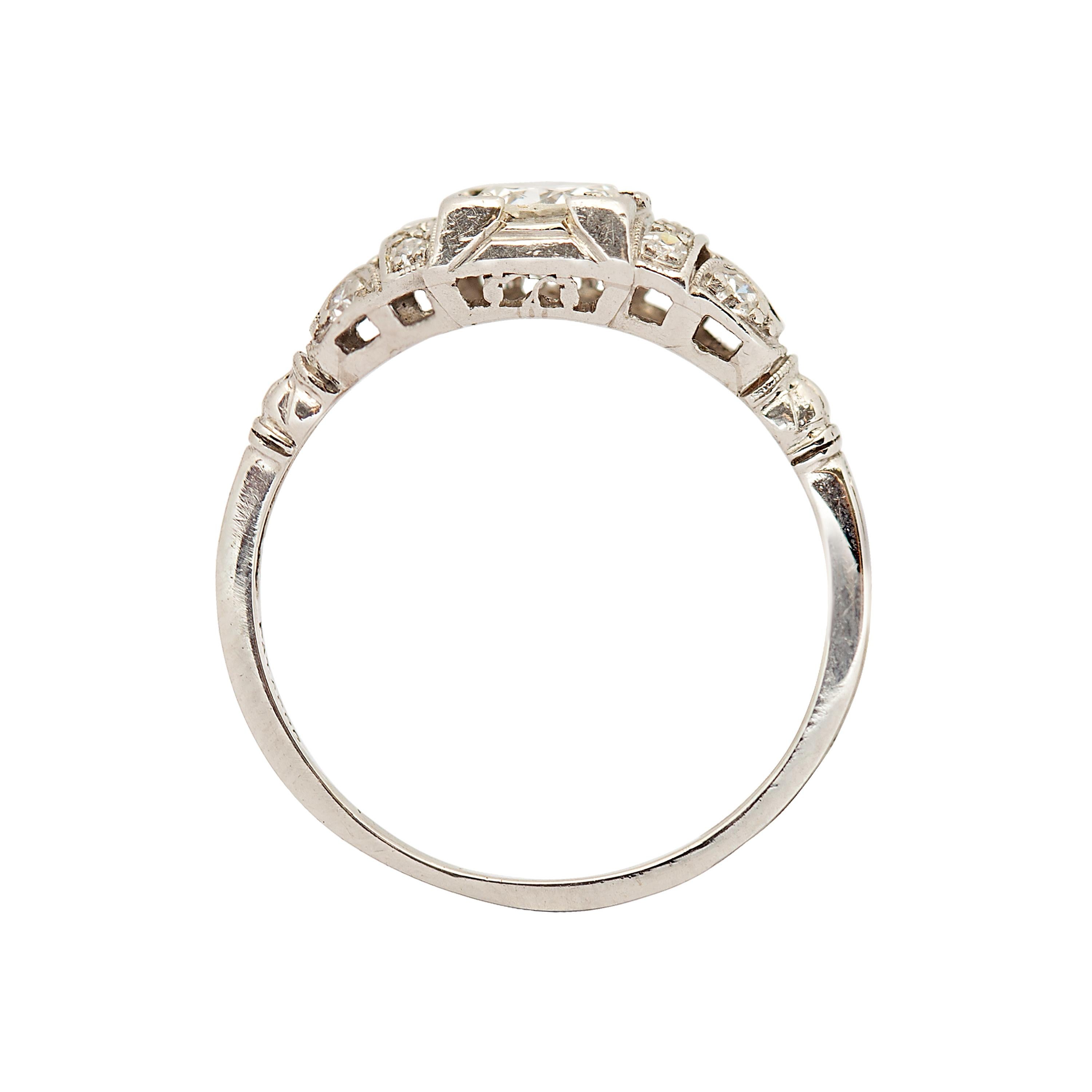 A truly captivating piece, this Edwardian-era platinum engagement ring features a dazzling G-colored, VS1 clarity diamond weighing approximately 0.40 carats at its center. The diamond’s exceptional brilliance is complemented by a row of three