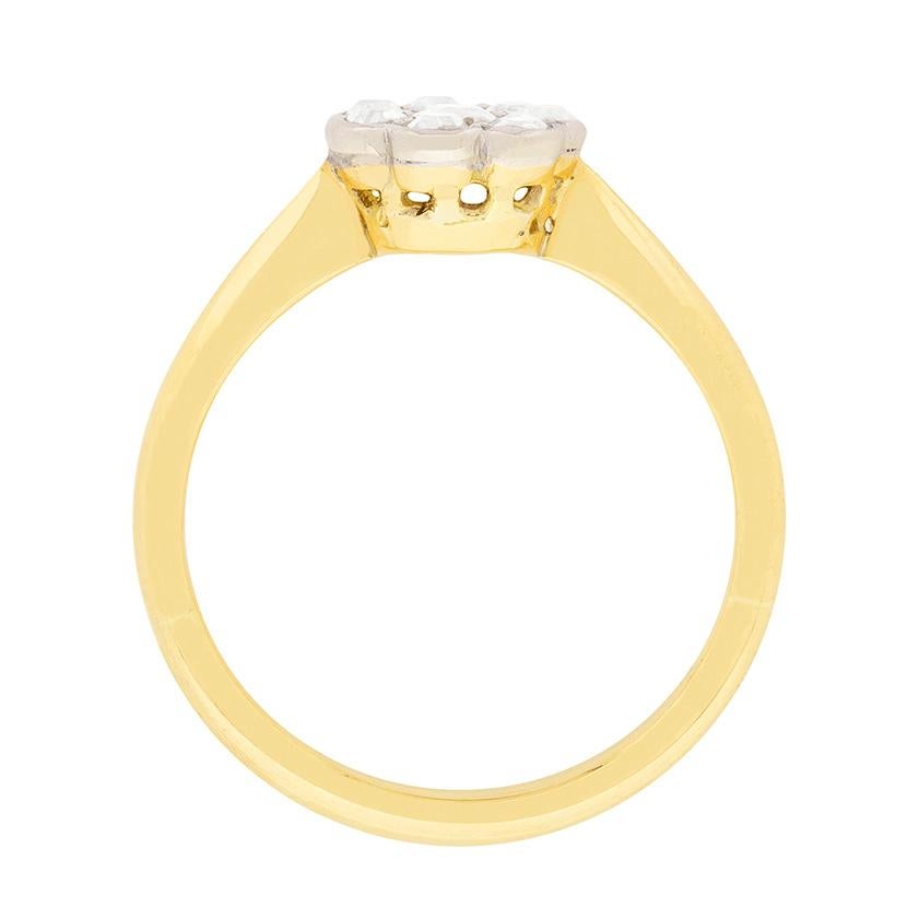 An Edwardian era rendition of a classic style. This beautiful rings comprises of old cut diamonds arranged in a daisy design and grain-set in platinum over 18 carat yellow gold. The stunning stones are G in colour and VS in clarity, meaning they