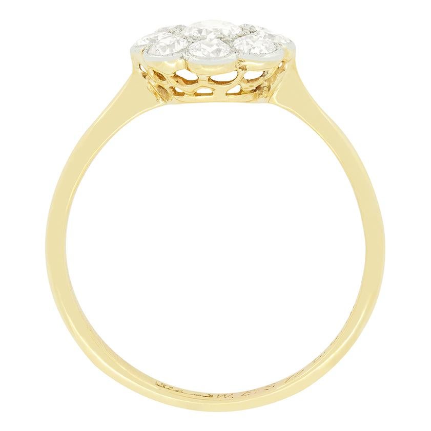 This delightful Edwardian cluster ring features a 0.20 carat central old cut diamond, surrounded by eight 0.05 carat diamonds. Each stone is delicately grain set into platinum, creating a daisy like cluster. All the diamonds match in quality at G in