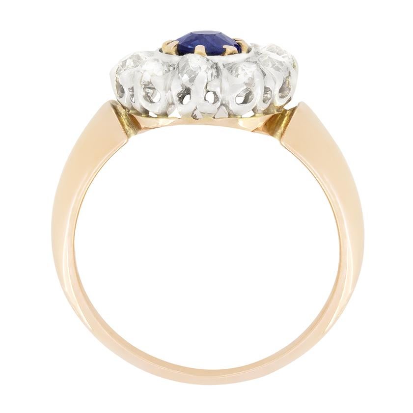 Este impresionante anillo eduardiano en racimo presenta un zafiro natural de 0,60 quilates de talla ovalada en su centro. El zafiro azul profundo está engastado en oro amarillo de 18 quilates y rodeado de un halo de diamantes talla antigua. Los