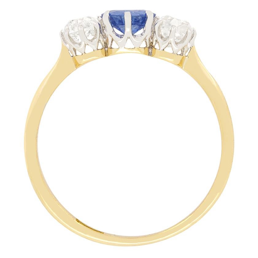 A light blue sapphire is flanked by diamonds in this wonderful Edwardian trilogy ring. The central sapphire is an old cut stone, weighing 0.60 carat. The diamonds match in size at 0.35 carat, with all three stones being claw set into a platinum