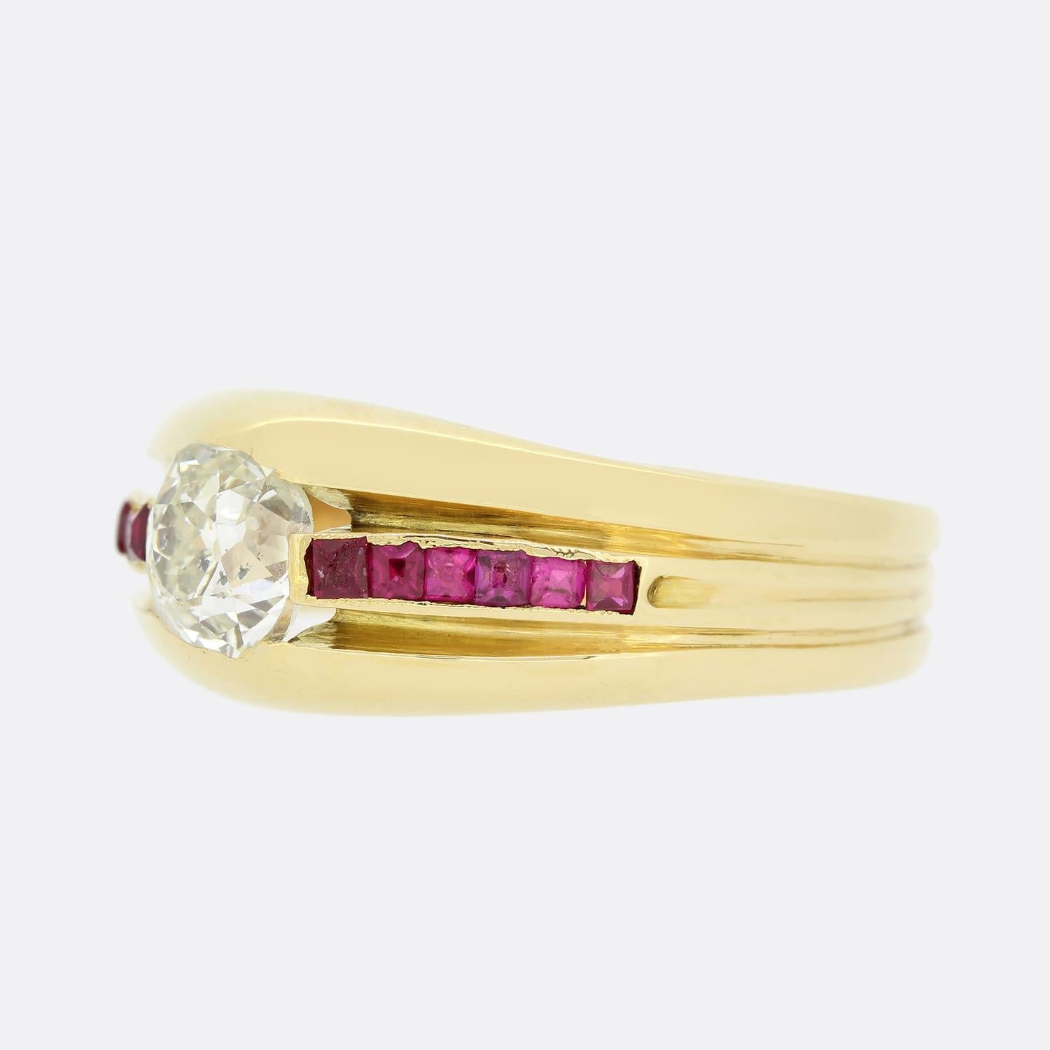This is an 18ct yellow gold diamond solitaire ring. The ring is set with a central 0.65 carat old cut diamond and 6 square cut rubies on each shoulder. The bright white sparkle of the diamond is highly complimented by the rich red hue of the