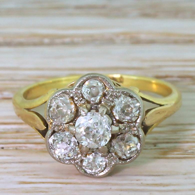 A very lovely antique diamond cluster ring. The centre old cut diamond is claw set and surrounded by a further six, slightly smaller, old cuts which are rubover and milgrain set in platinum. Very pretty “U” detailing in the gallery leading to