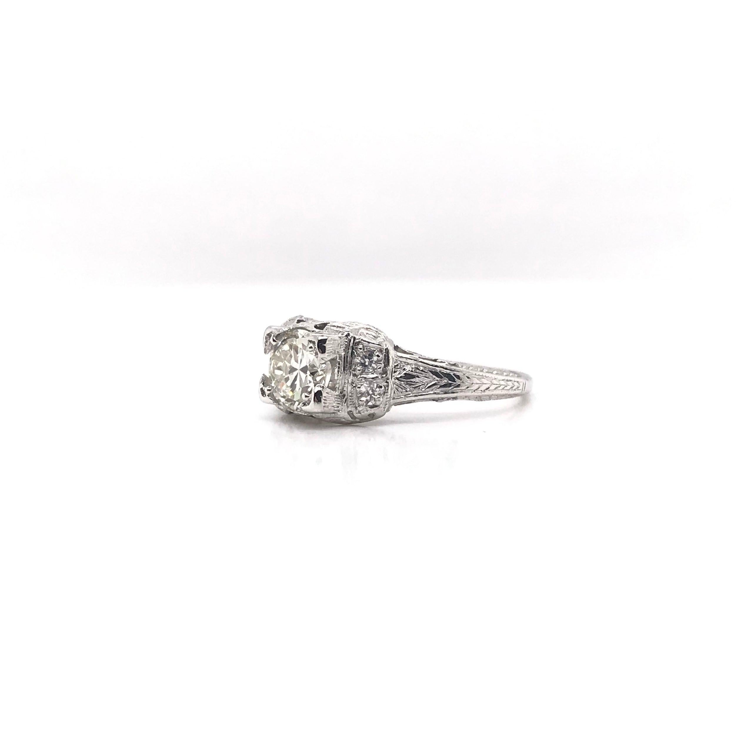 This antique piece was handcrafted sometime during the Edwardian design period ( 1900-1915 ). The platinum filigree setting features a gorgeous 0.74 carat center diamond that grades J in color, SI1 in clarity. The setting features enchanting floral