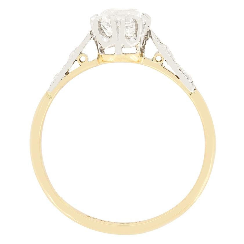 This beautiful Edwardian solitaire ring features a 0.855 carat old cut diamond at its centre. The sparkling diamond is of H colour and SI1 clarity and has been claw set into a platinum collet. Down each shoulder and additional two small diamonds are