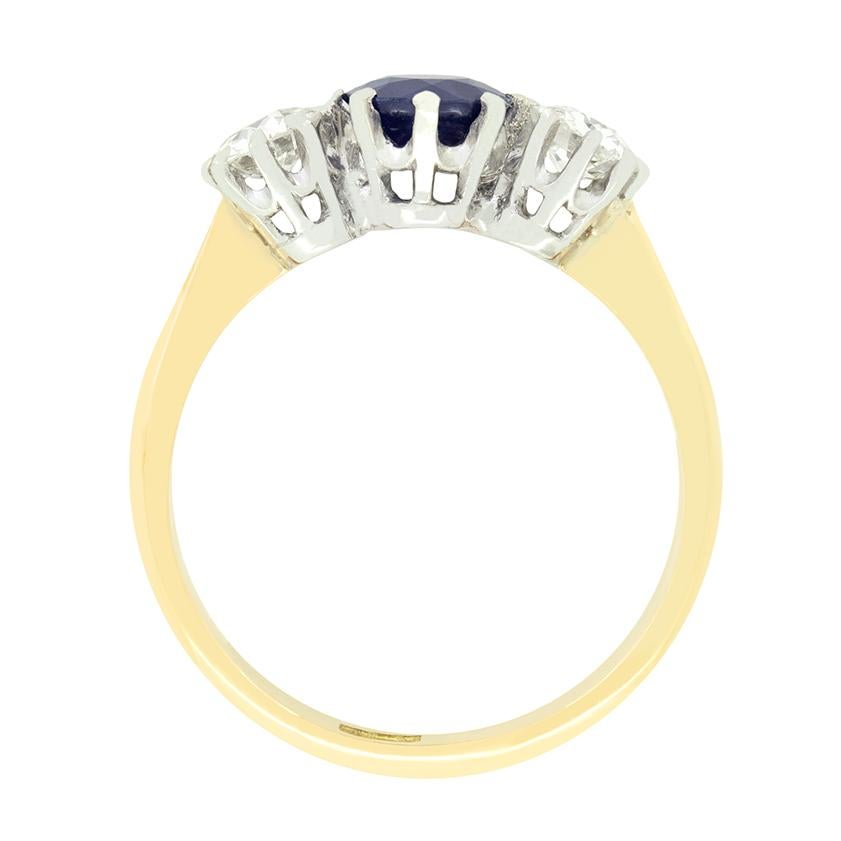 This stunning Edwardian three stone ring features a natural blue Sapphire at it's centre, flanked by a pair of old cut diamonds. The sapphire is a 0.85 carat, unheated old cut stone. The two diamonds are 0.35 carat a piece and match in quality at G