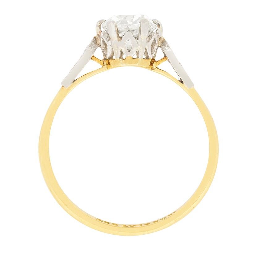 Dating to between 1900 and 1910, this diamond solitaire is hand made. It features a claw set old cut diamond weighing 0.88 carat. It is an old cushion cut which is a hand cut diamond and is graded as H in colour and VS2 in clarity. On the shoulders