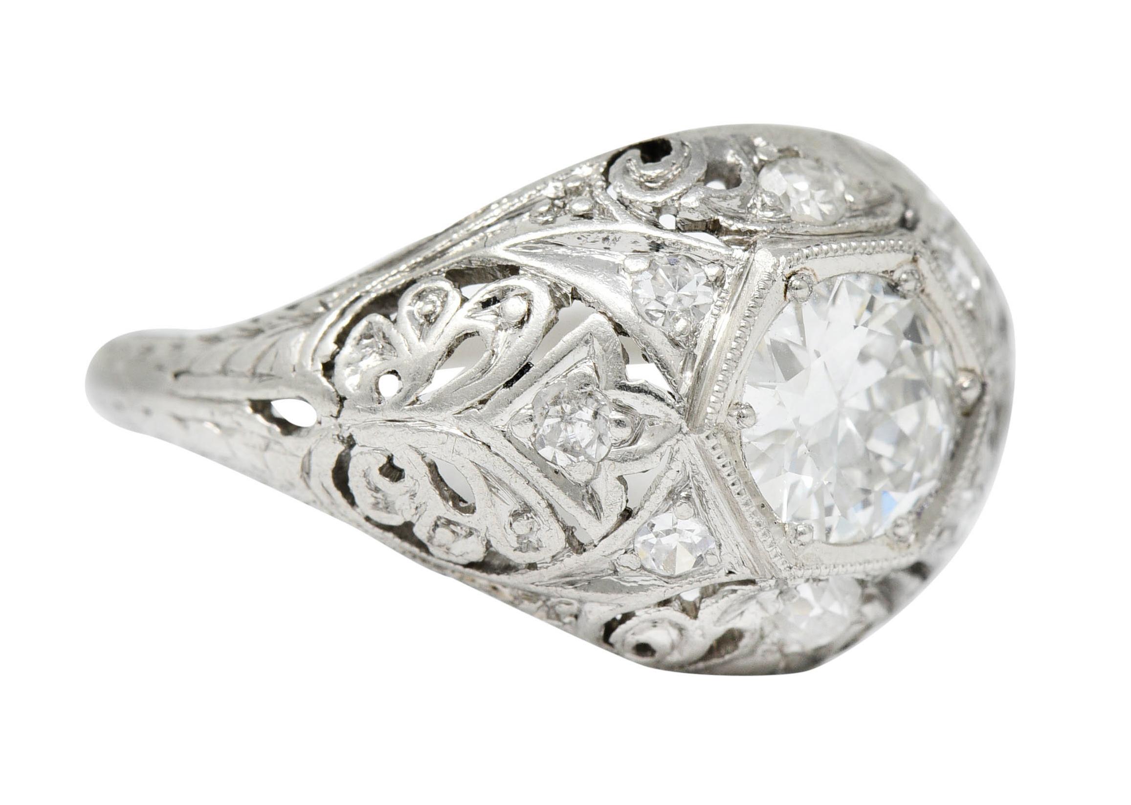 Centering a transitional cut diamond weighing approximately 0.65 carat - H color with SI1 clarity

Set in a hexagonal head of an intricately pierced bombè style band - featuring scrolling foliate throughout

Accented by old European and single cut