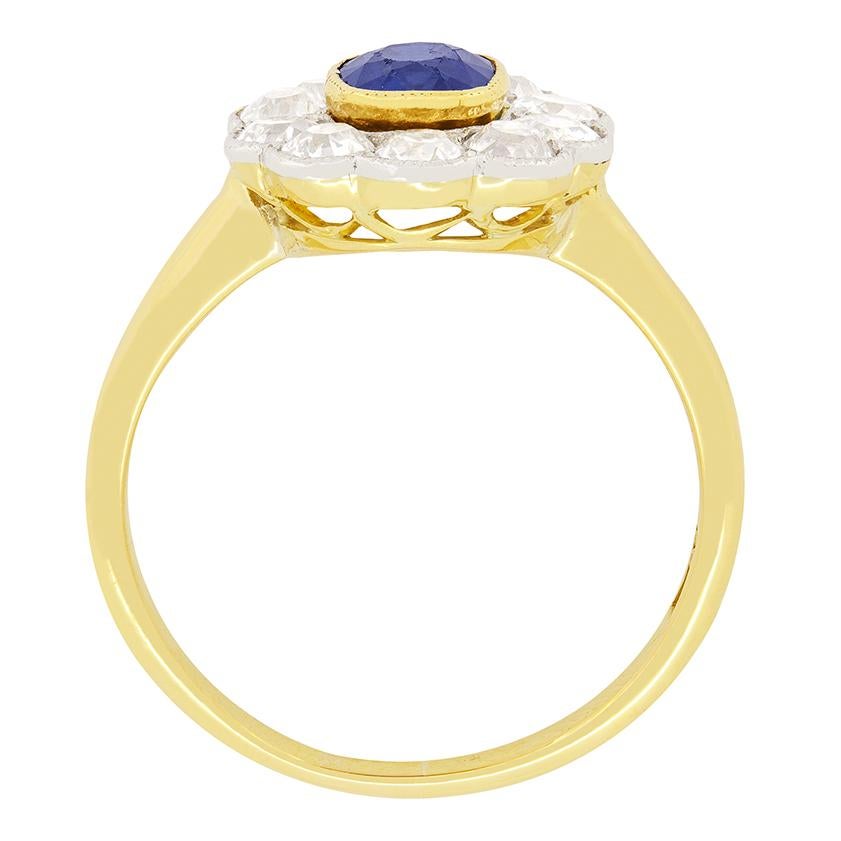 Dieser wunderschöne edwardianische Ring zeigt in der Mitte einen tiefblauen Saphir, der von zehn Diamanten im Altschliff umgeben ist. Der in 18 Karat Gelbgold gefasste Saphir wiegt 0,90 Karat und ist oval geschliffen. Die Diamanten des umgebenden