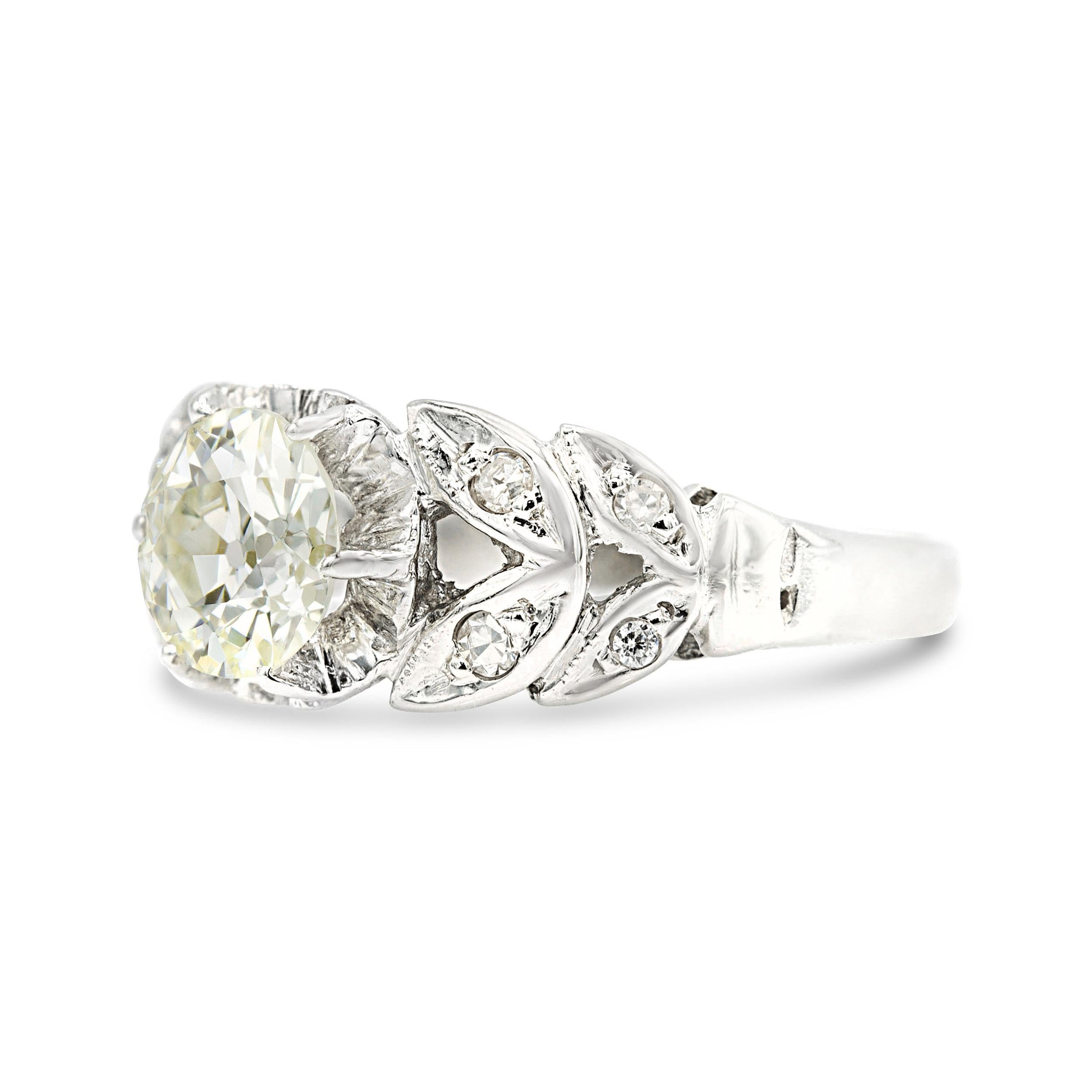 A beautiful and unique engagement ring by any standard, this Edwardian beauty stands out with its split shoulders and diamond-studded leaf motif design. The 0.96-carat center old European diamond weighs a touch under 1 carat but spreads as it weighs