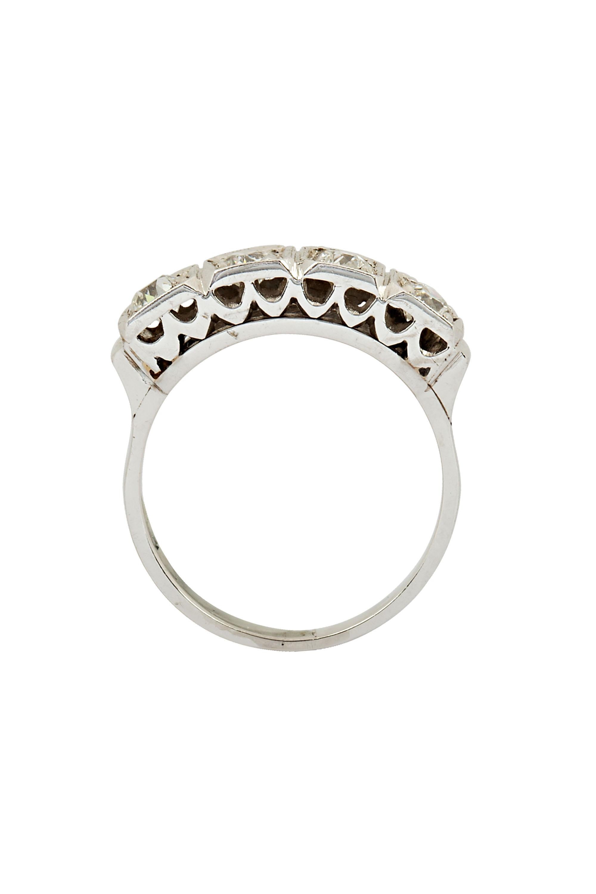 Crafted in platinum, this Edwardian era ring features a row of four dazzling European cut diamonds bead set in square frames The bold scale of the ring shank and scalloped gallery further enhance the strong lines of this handsome piece. The ring has