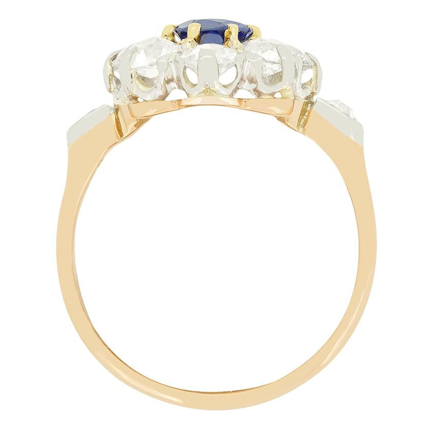 This stunning cluster ring dates back to the 1910s. At it’s heart sits a beautiful deep blue Sapphire claw set in contrasting 18 carat yellow gold. The oval cut stone weighs 1.00 carat stone and is completely natural and unheated. Enveloping the