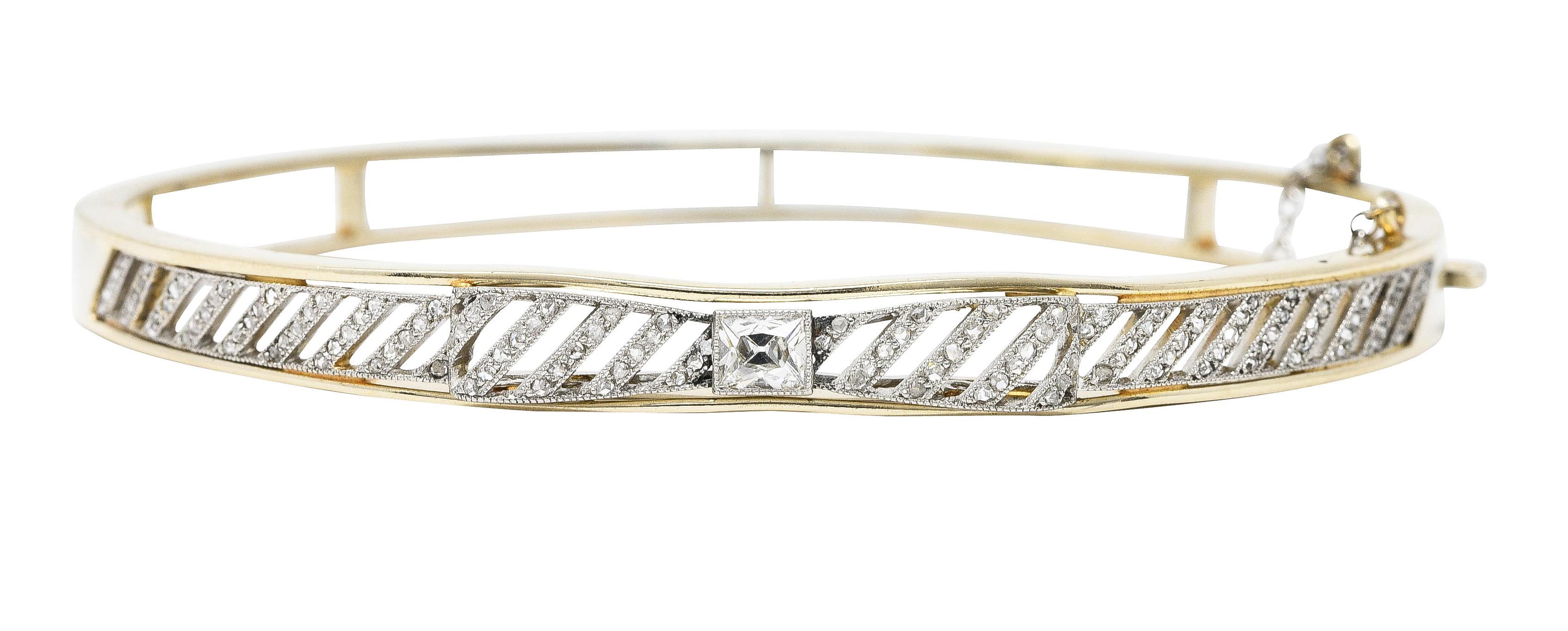 Designed as a gold bangle with a centralized dimensional platinum bow ribbon motif. Featuring a French cut diamond bezel set as the bow's knot - weighing approximately 0.40 carat. H color with VS clarity - flanked by pierced rows of rose cut