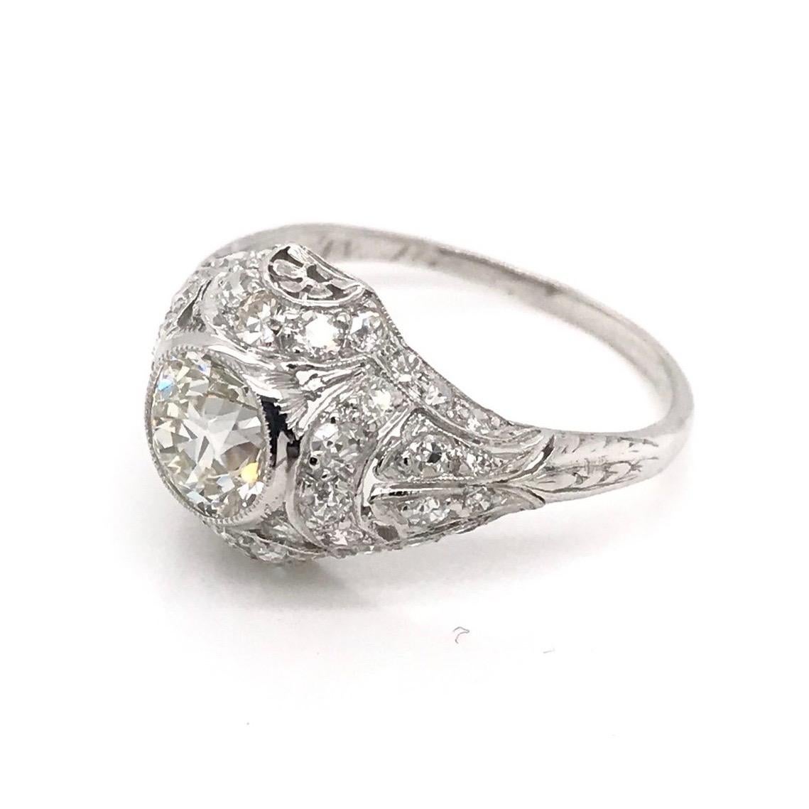 This antique piece was handcrafted sometime during the Edwardian design period ( 1900-1920 ). The intricate filigree setting is platinum and features a center Old European Cut diamond measuring approximately 1.05 carats. The center diamond grades K