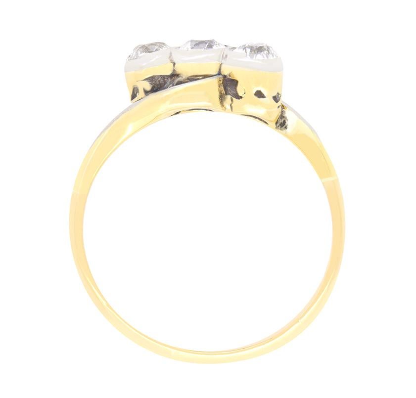 Questo anello edoardiano, che rappresenta una bellissima rivisitazione del classico design a trilogia, presenta tre scintillanti diamanti taglio vecchio incastonati in diagonale al centro. Ogni diamante ha una dimensione di 0,35 carati con colore H