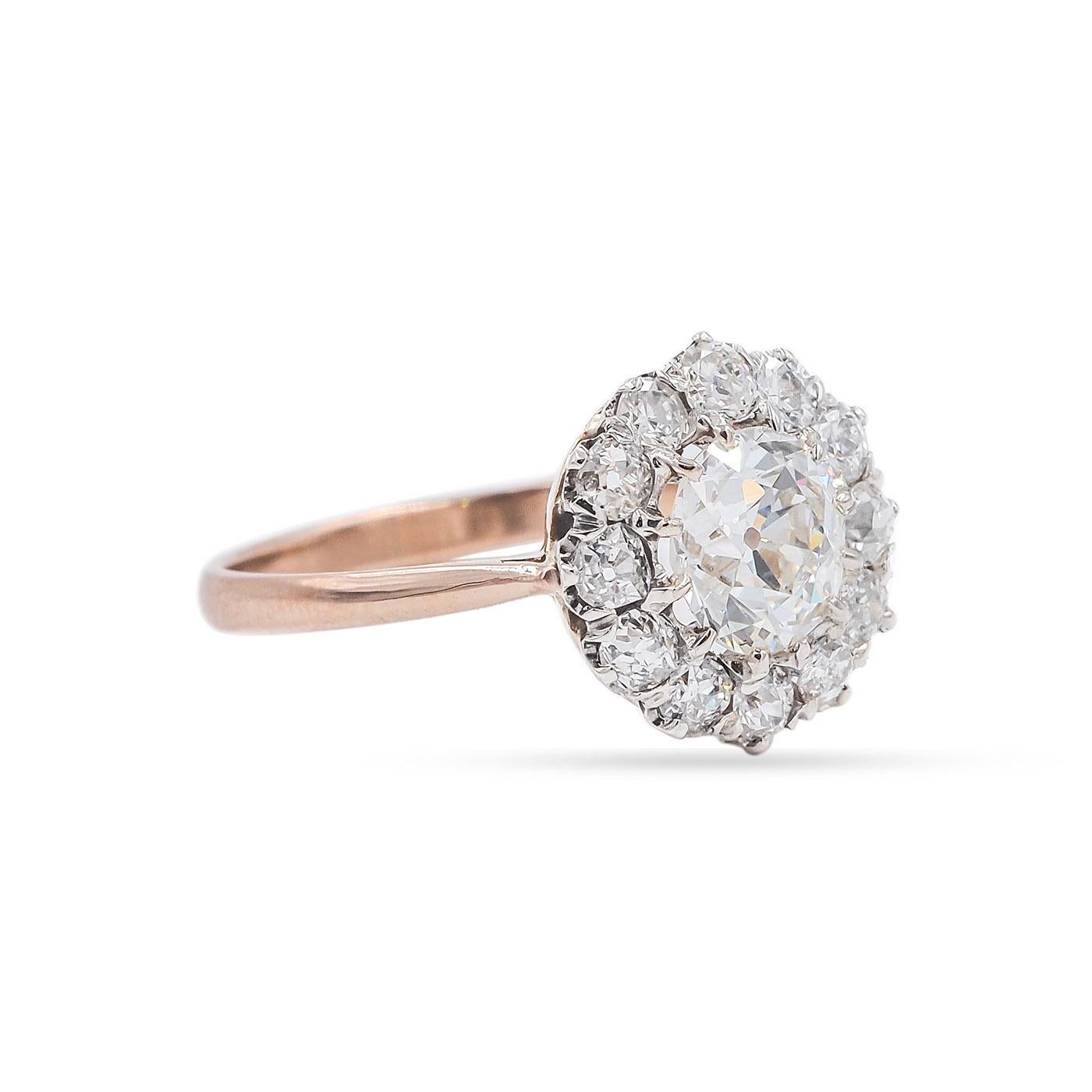 A classic Edwardian era 1.08 Carat Old European Cut Diamond Cluster Engagement ring composed of 14k rose gold and platinum. The center stone 1.08 Carat is GIA certified J color/VVS2 clarity. Surrounded by a halo of 12 diamonds, a mix of Old Mine Cut