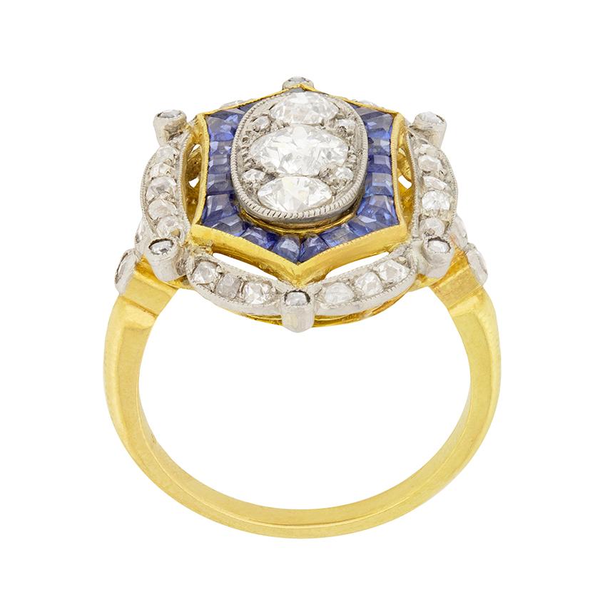 This ornate Edwardian ring features old cut diamonds and sapphires set in 18 carat yellow gold and platinum. The centre diamond is 0.60 carat with a 0.25 carat diamond above and below. They are G colour and VS2 clarity. A halo of 0.66cts of