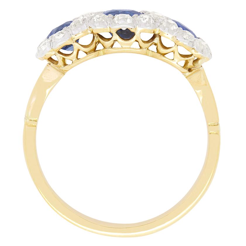 A stunning example of Edwardian craftsmanship, this exquisite trilogy halo ring showcases three vivid blue sapphires enrobed in old cut diamonds. The central sapphire sits the largest at 0.50 carat with the flanking pair at 0.30 carat a piece.